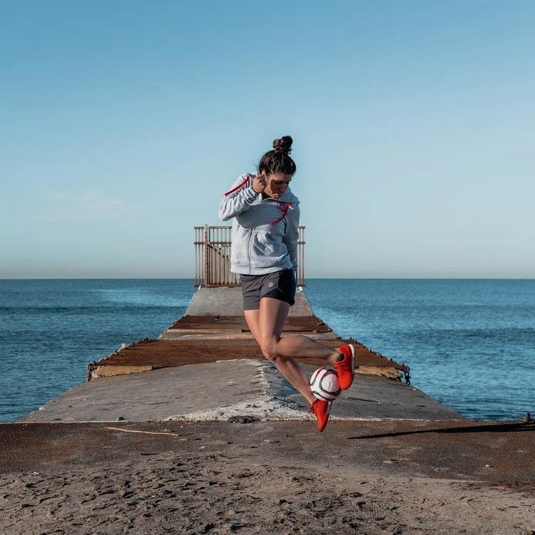 Woman with soccer ball by the ocean