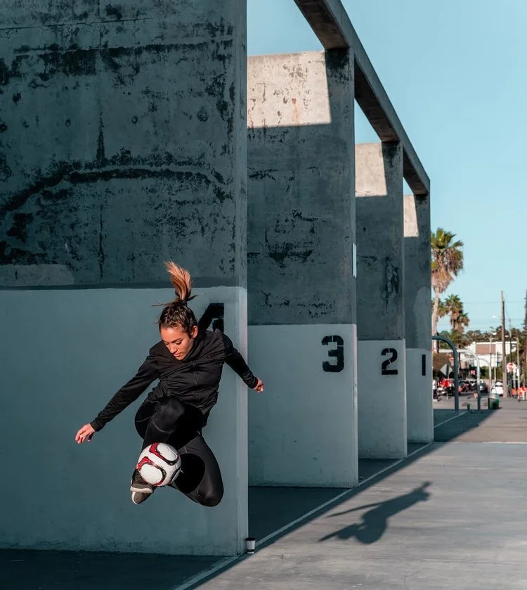 Woman jumping with a soccer ball in the streets