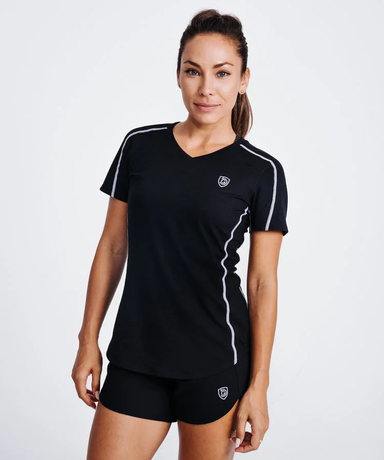 Woman standing in front of white background wearing an all black soccer outfit