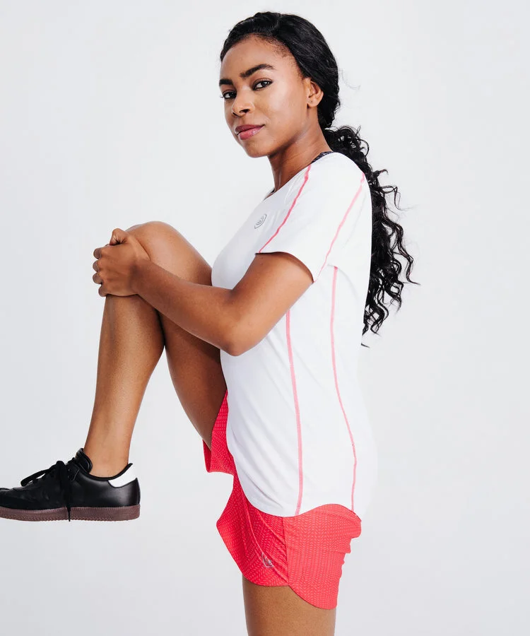 Woman standing in front of white background holding knee in the air