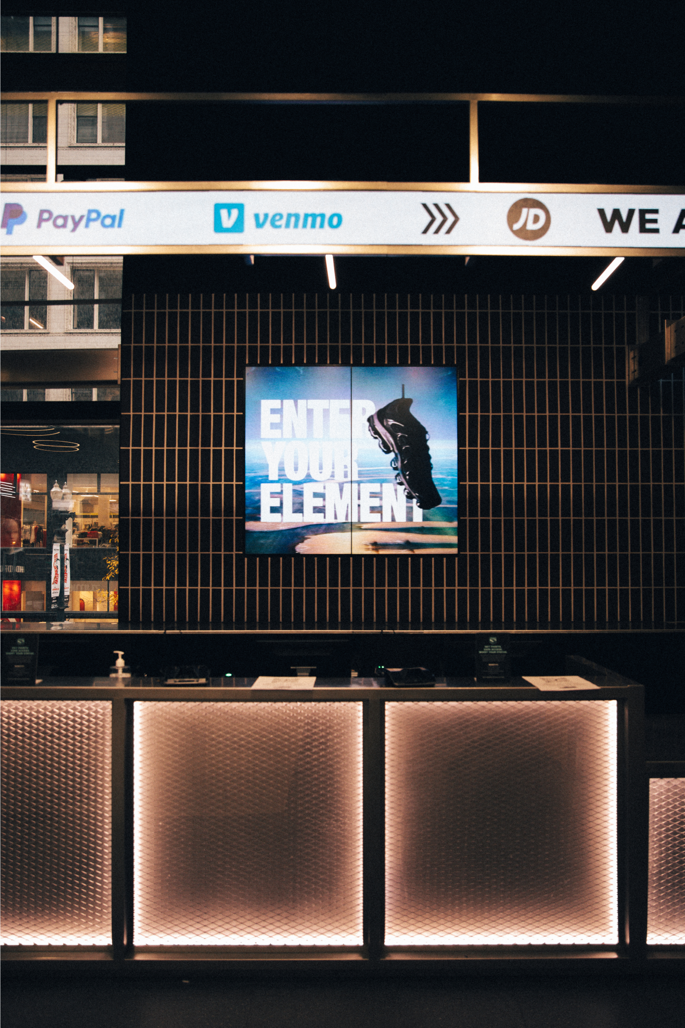 Screen behind kiosk desk inside JD Sports