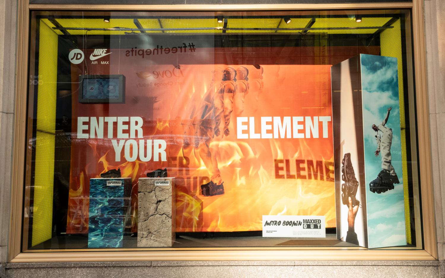 Retail window of Metro Boomin in fire with text that reads "Enter your element" and shoes on display