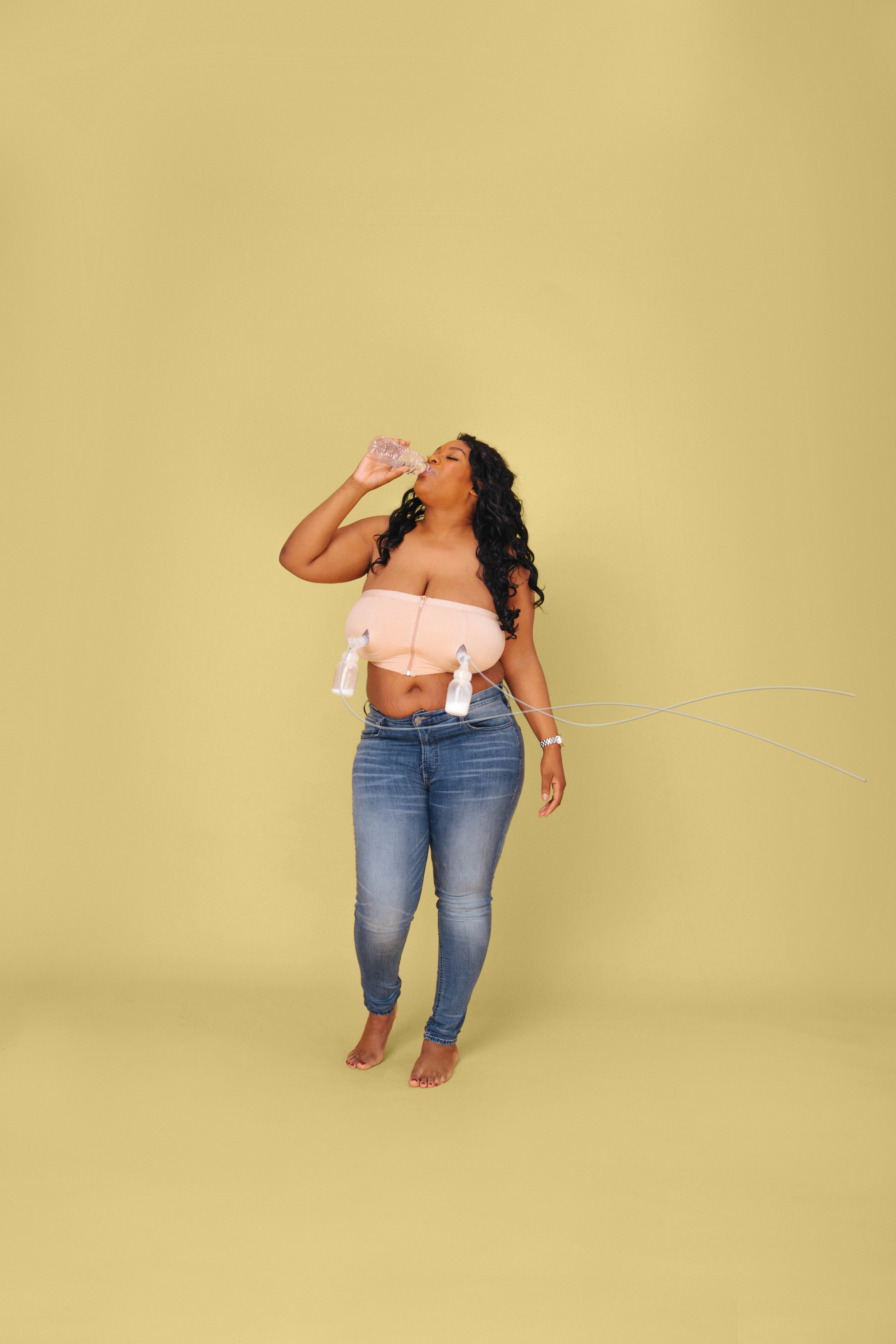 Mom standing in front of yellow background with breast pumps