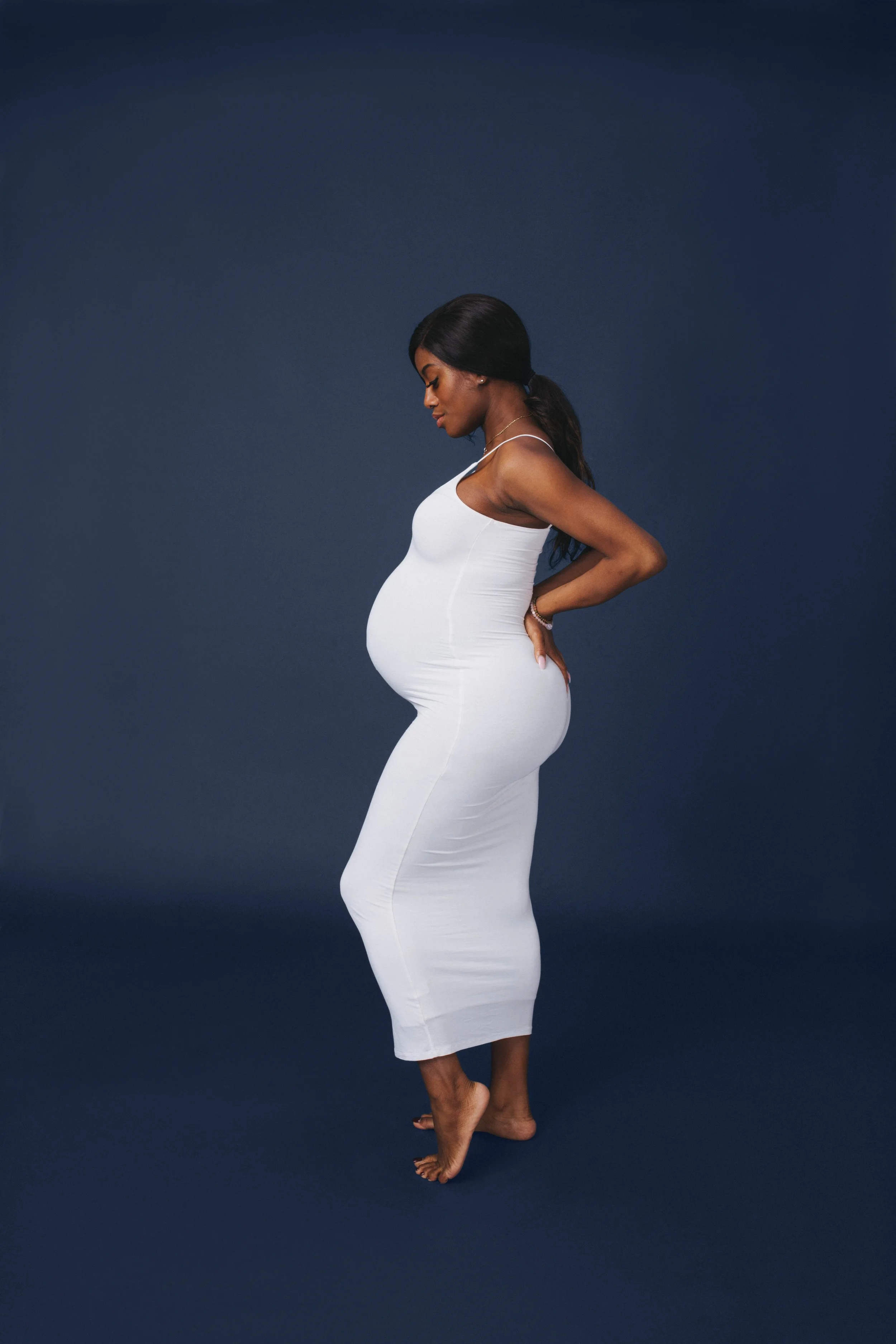 Pregnant mom in white dress infront of blue background