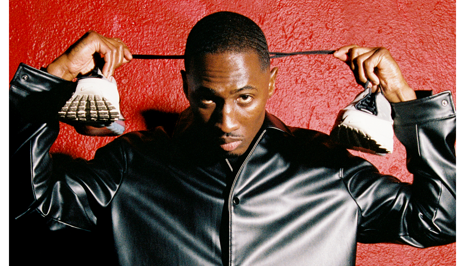 Man holding Nike Air Max in front of red background