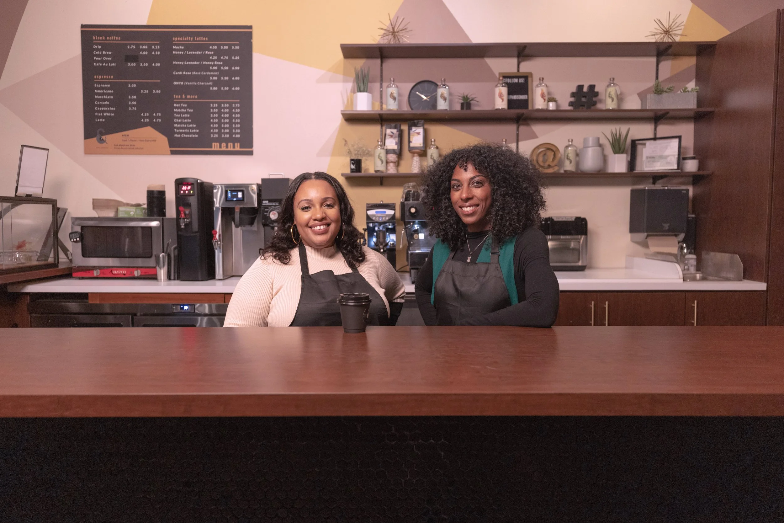 Two women standing behind coffee counter