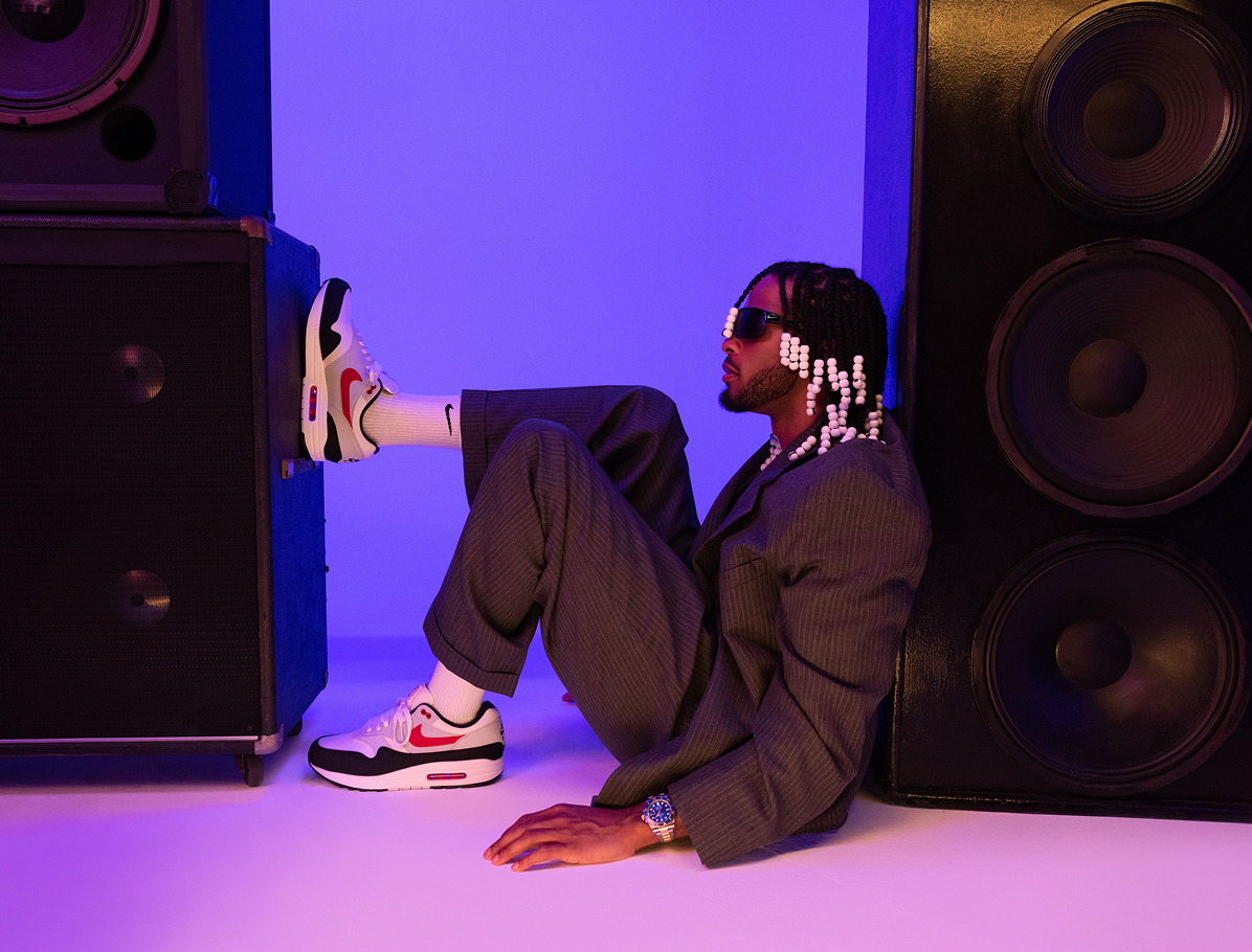 Armani White sitting between speakers