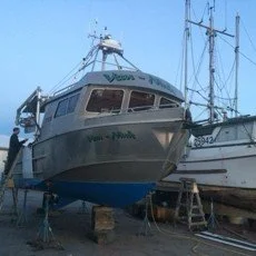 A large boat on land with scaffolding and another boat nearby. KNW Diesel provide installation, sales and service of Marine engines Scania, FPT, Moteurs Baudouin in British Columbia
