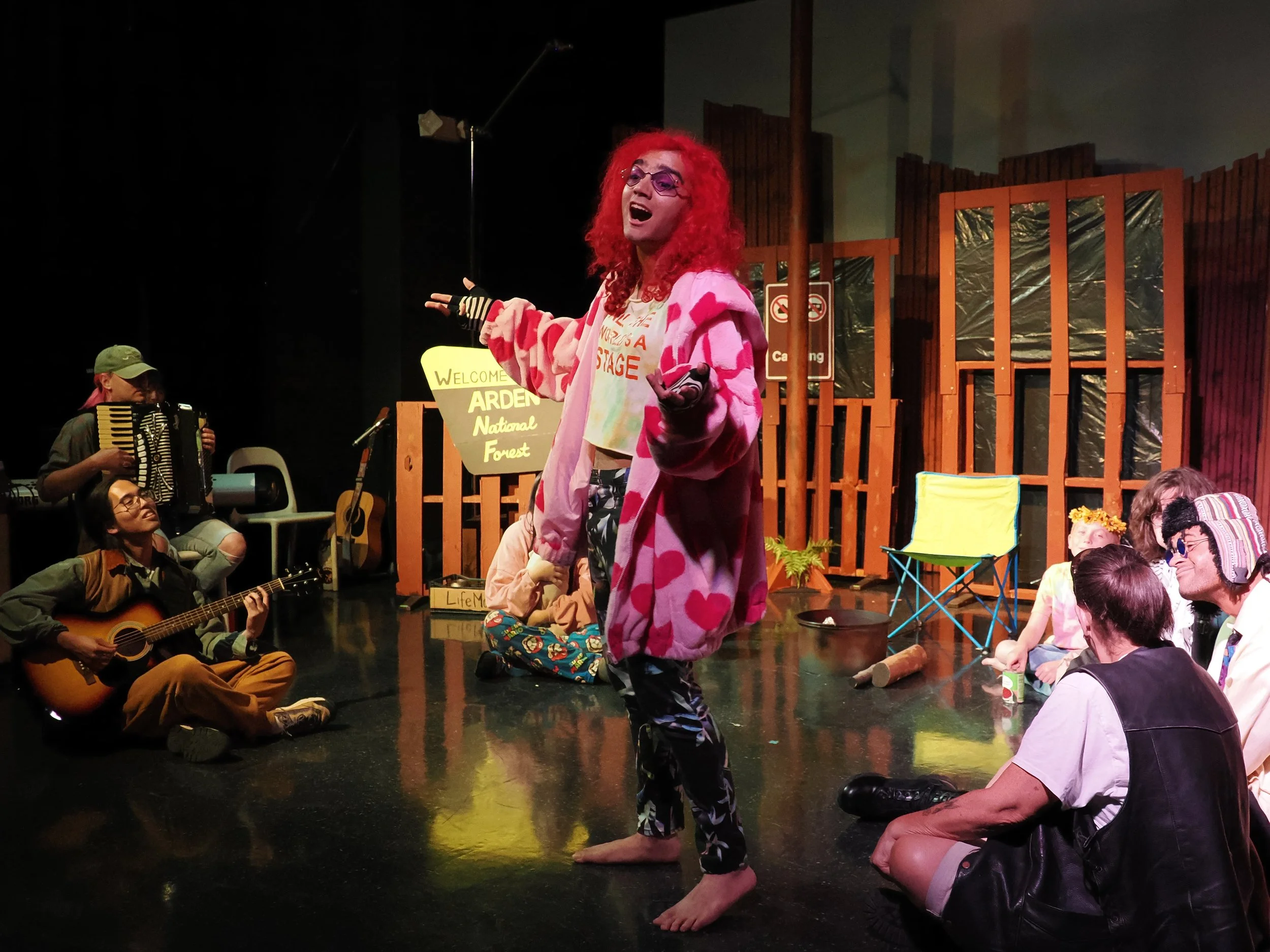 Jaques (Talia Sabbag) entertains a camp of street musicians and exiled Foresters (Joaquin Gawchua, Rory Kinsolving, Moe Salas-Smith, Neil Birkle, Karol-Ann Coleman, Francisco "Frankie" Vargas, Christopher Rozier).