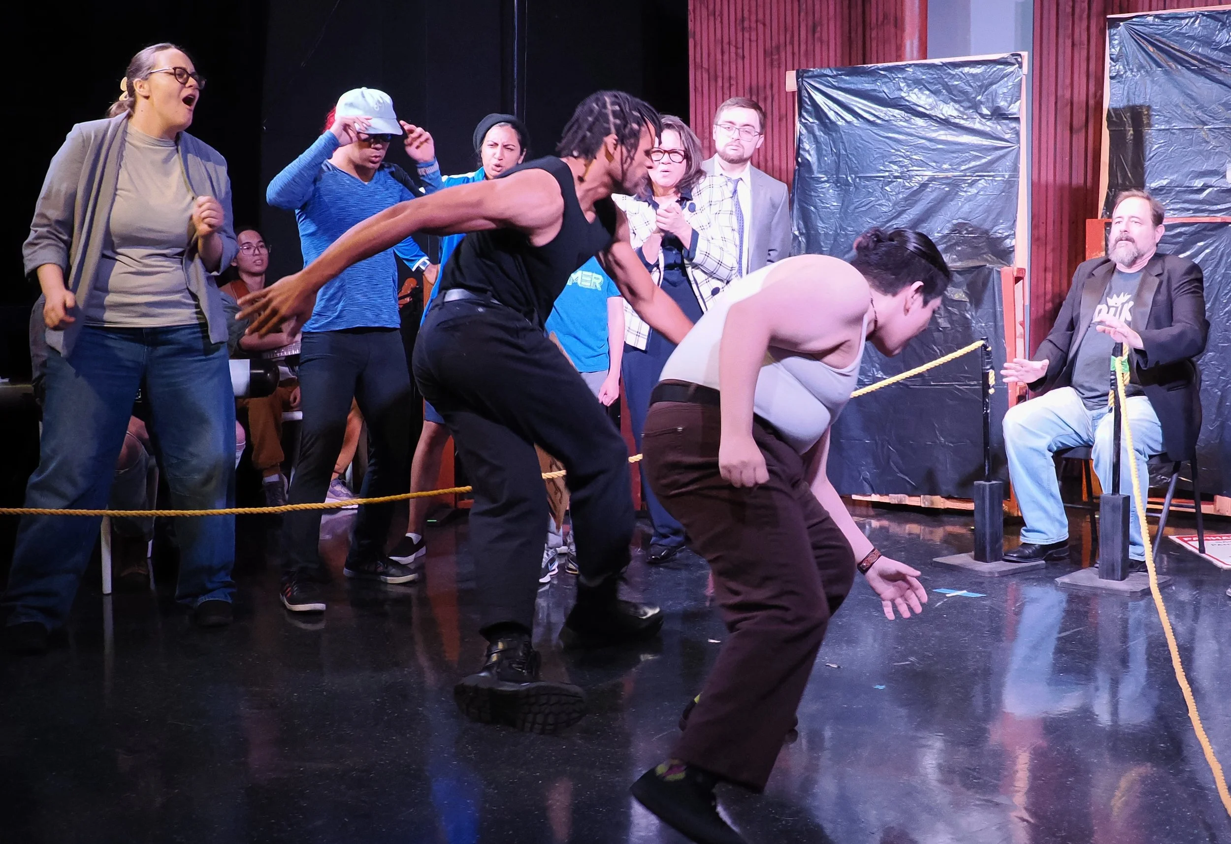 Orlando (Caiden King) finally lands a punch on Charles the Wrestler (Christopher Rozier), to the dismay of the crowd (Left to right: Molly Buck, Joaquin Gawchua, Talia Sabbag, Divya Pillai, Karol-Ann Coleman, Andrew Richmond, Barry Smith).