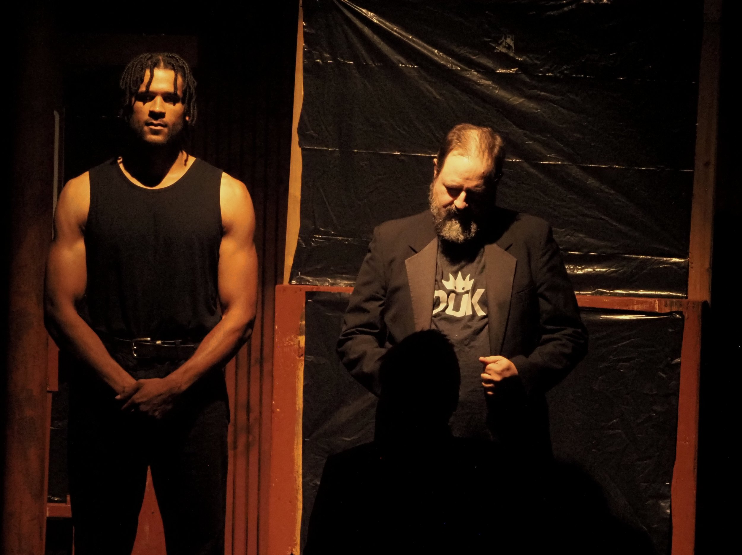 Duke Frederick (Barry Smith) interrogates Oliver (Andrew Richmond) as Charles the Wrestler (Christopher Rozier) stands guard.