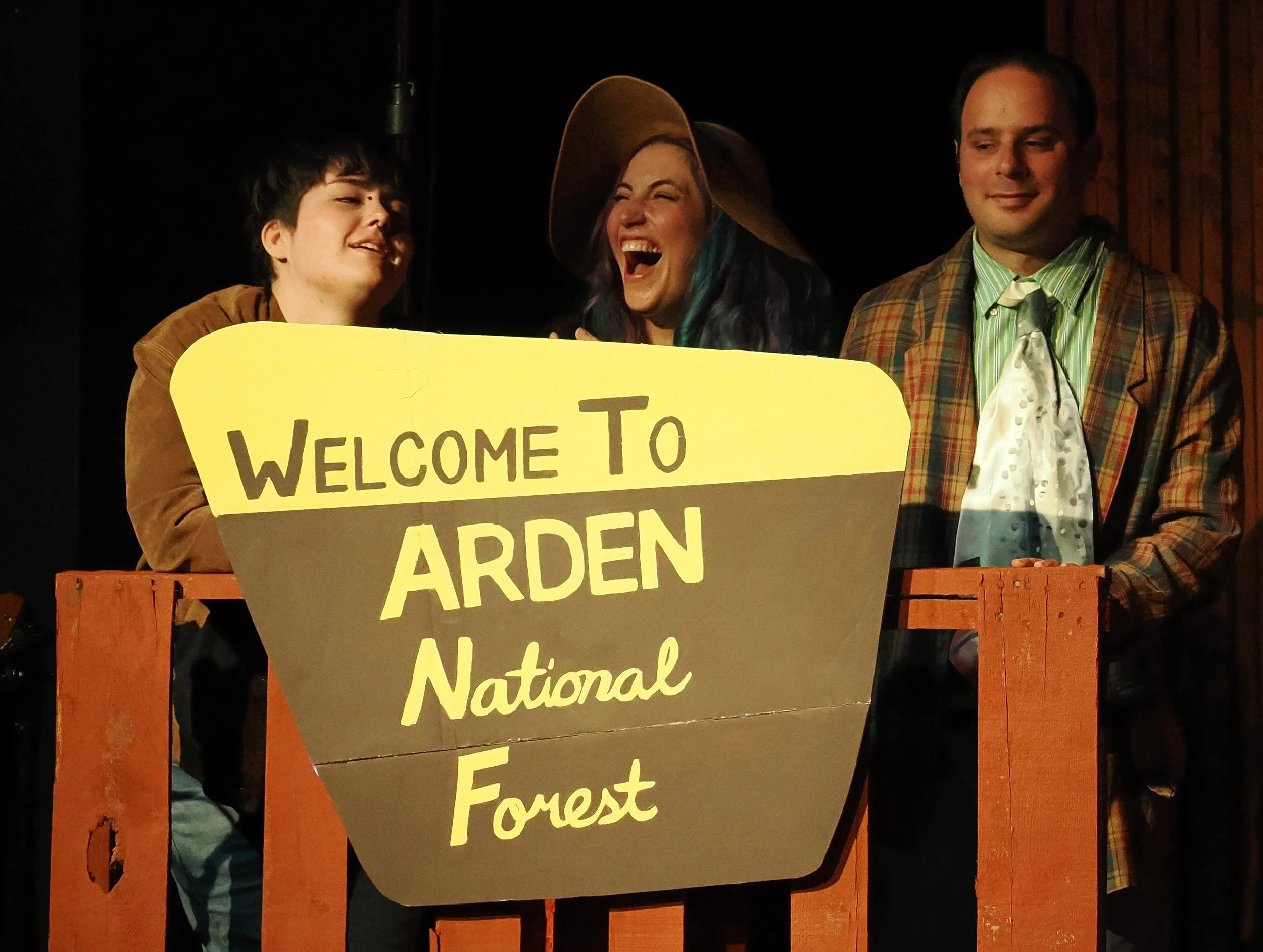 Rosalind, now in disguise as Ganymede (Quinn Trixx); Celia, now in disguise as Aliena (Evie Bennett), and Touchstone (Kenny Silberburg) sneakily observe their new forest home.