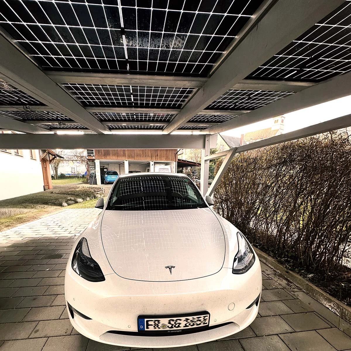 Weißer Tesla Model Y unter einem Solarcarport