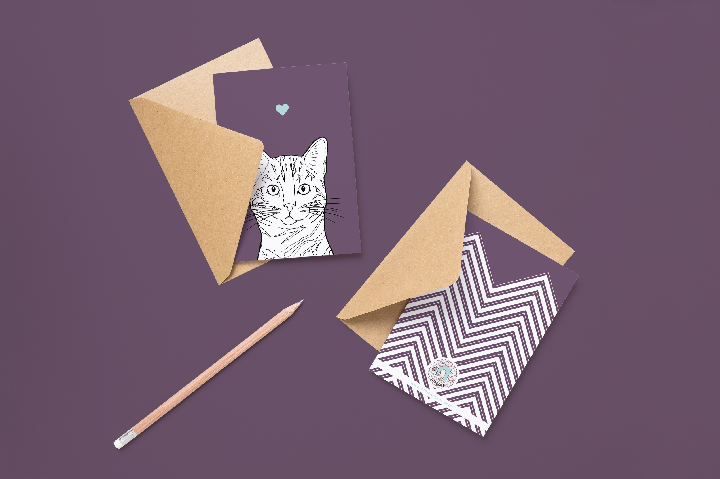 Two cards on brown envelopes, one face up one down. The card and image have a deep purple coloured background, with a black & white digital illustration of the head & shoulders of a Bengal cat.