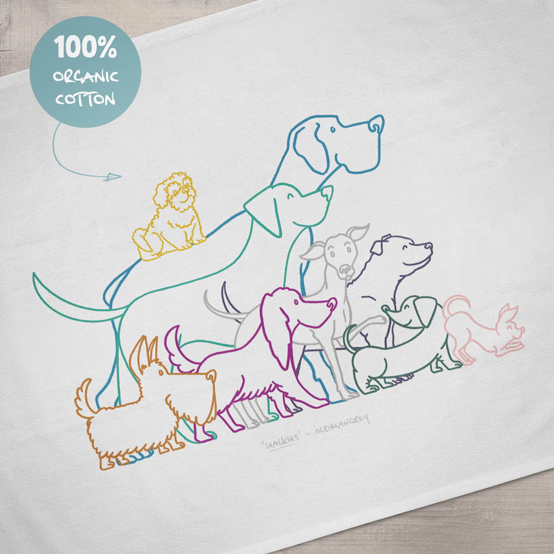 A close up of the design on a large tea towel. It has a colourful digital illustration of 9 dogs eager for walkies. A sign says '100% organic cotton'.