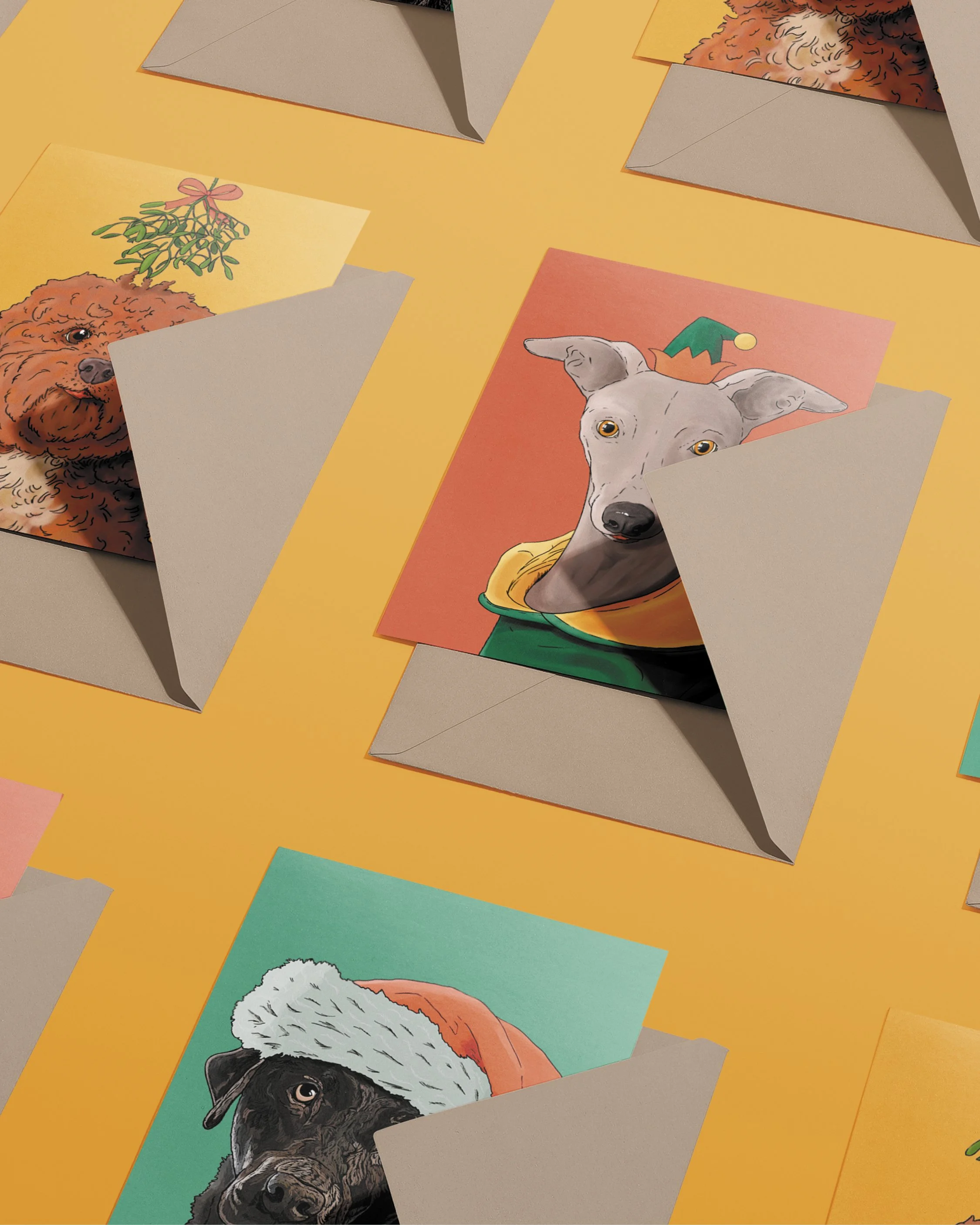 3 x A6 Dog Christmas Cards, bright digital illustrations including a Whippet in a green & red elf hat! Copies tucked into brown envelopes, set on a flat yellow gold background.