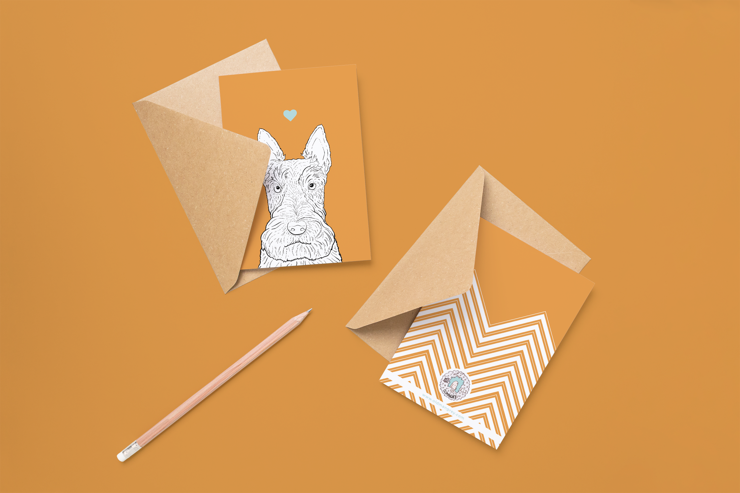 Two cards on brown envelopes, one face up one down. The card and image have an orange coloured background, with a black & white digital illustration of the head & shoulders of a Scottie dog.