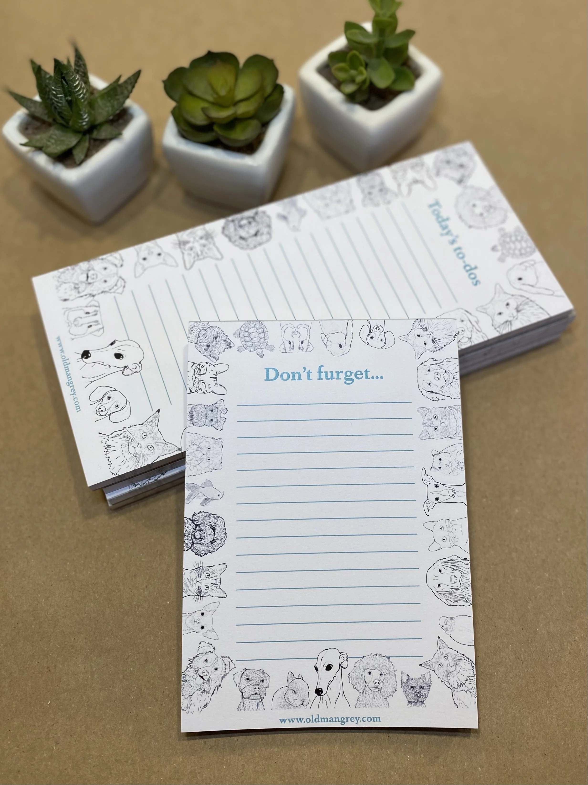 An A6 memo pad titled 'Don't Furget'. It has a black & white border of digitally illustrated pets! Leaning on a pile of longer pads in the same style, titled Today's To Do.