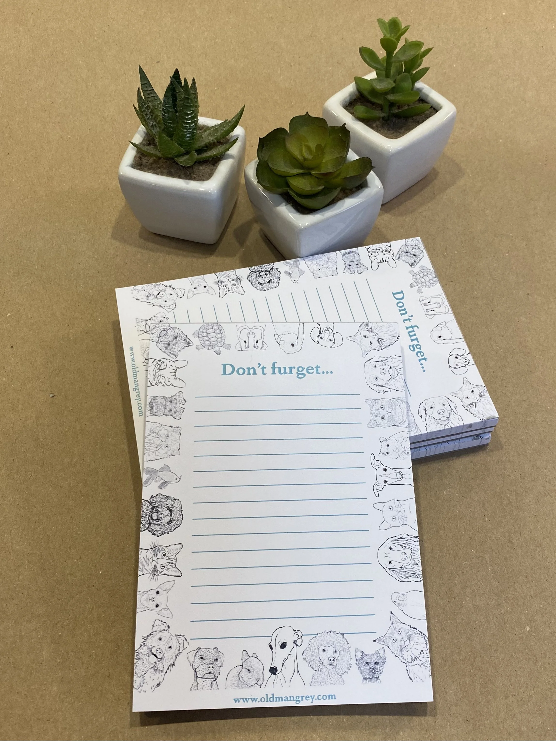 An A6 memo pad titled 'Don't Furget'. It has a black & white border of digitally illustrated pets! Leaning on a pile of longer pads in the same style, titled Today's To Do.