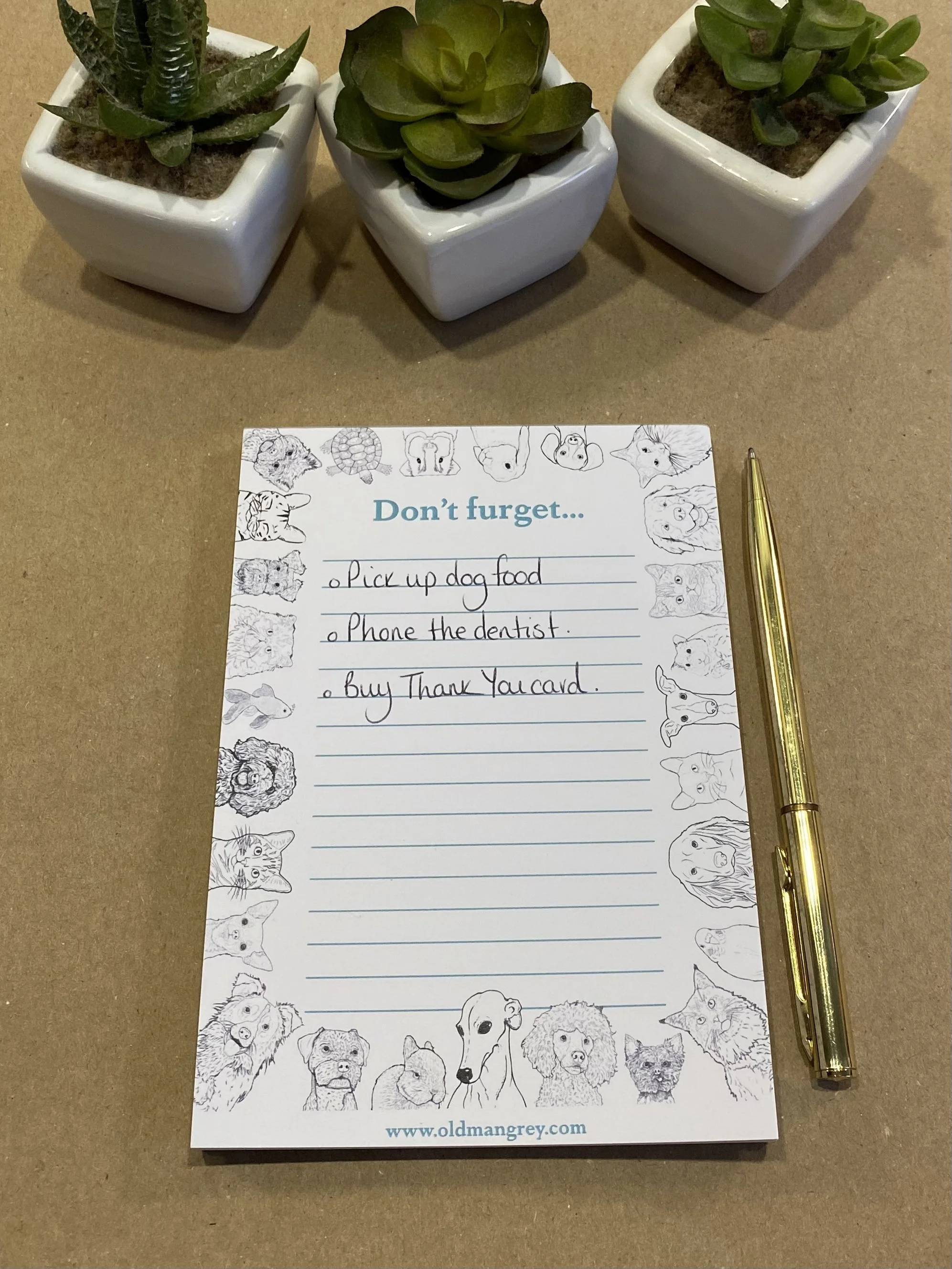 An A6 memo pad titled 'Don't Furget'. It has a black & white border of digitally illustrated pets! On brown paper, with a gold pen at the side, & 3 to do items listed.