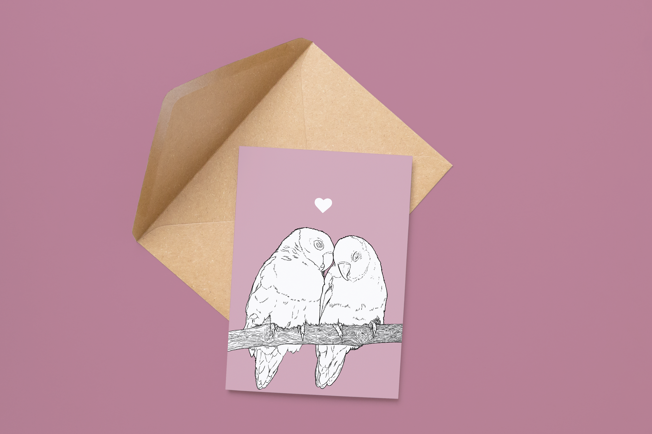 An A6 greetings card on a brown envelope. The card & image have a lilac purple background, with a black & white digital illustration of two Lovebirds sat on a branch.