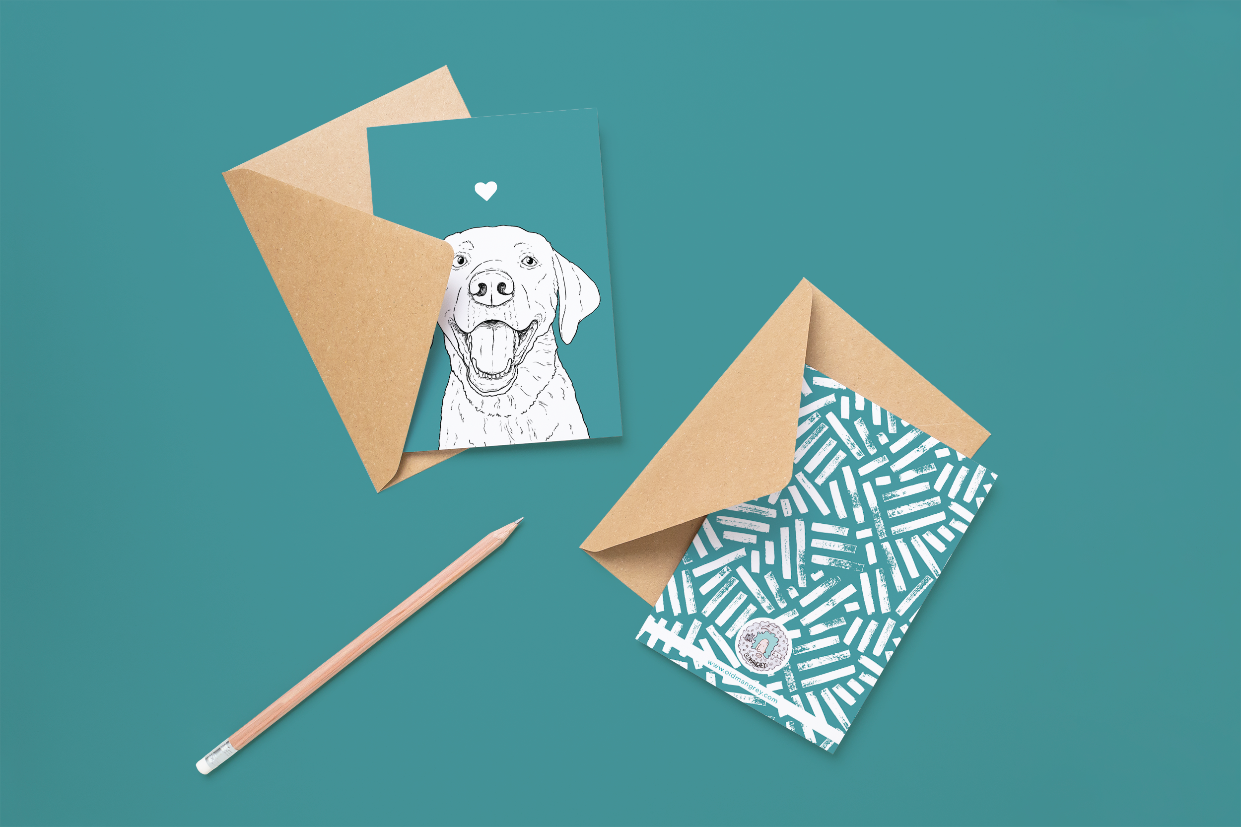 Two cards on brown envelopes, one face up one down. The card and image have a teal coloured background, with a black & white digital illustration of the head & shoulders of a Labrador dog.