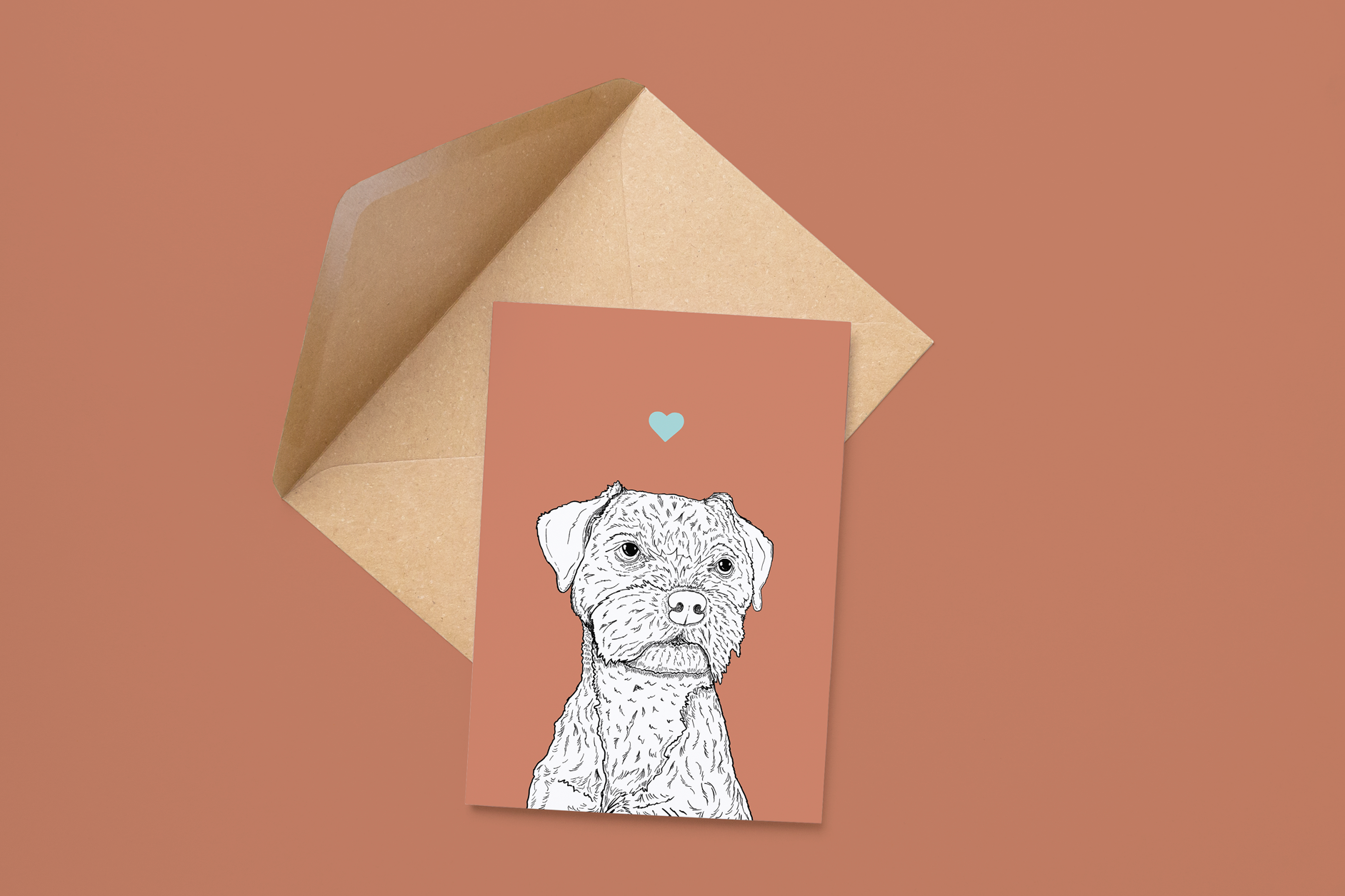 An A6 greetings card on a brown envelope. The card & image have a pink red background, with a black & white digital illustration of the head & shoulders of a Border Terrier dog.