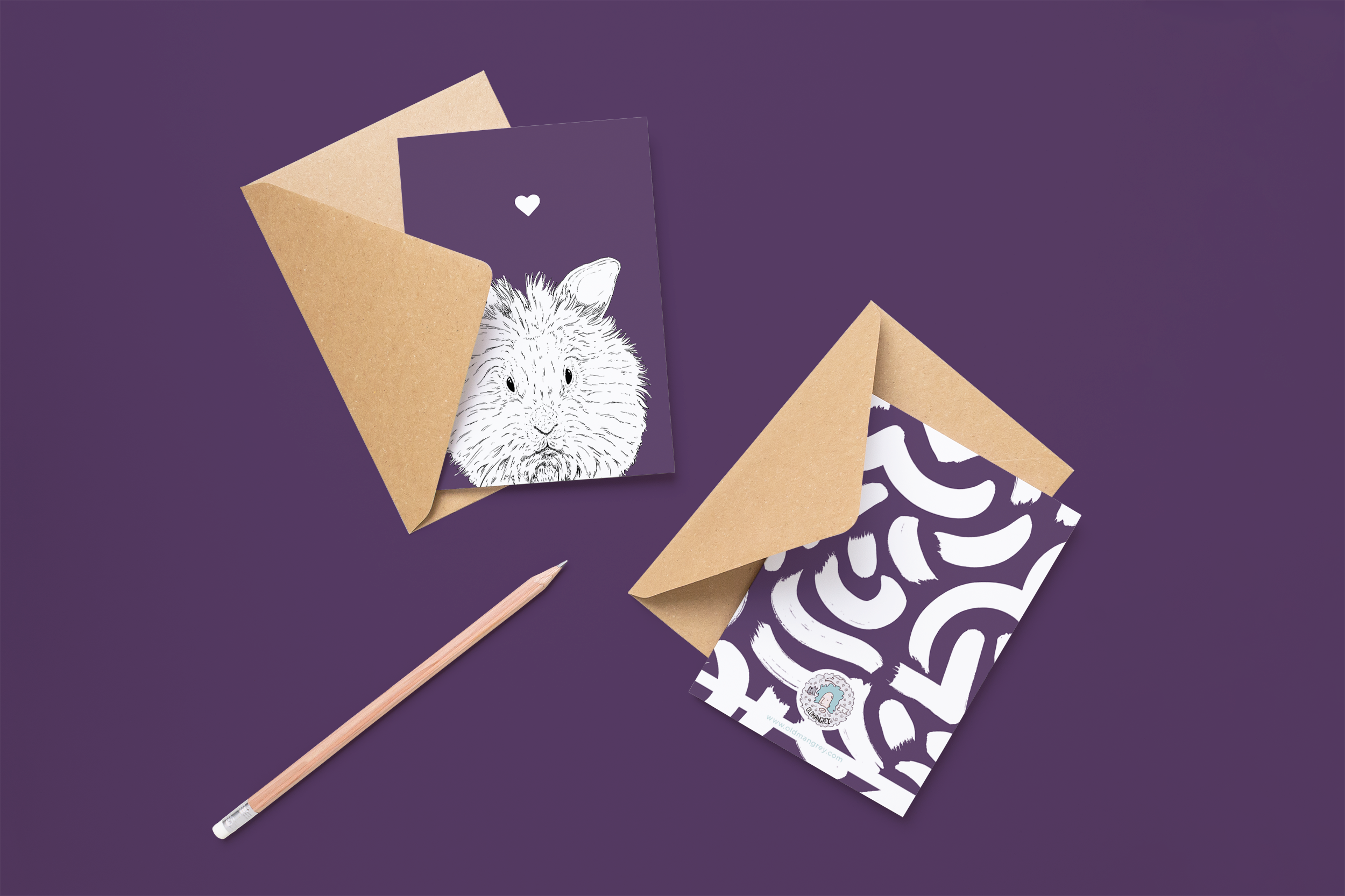Two cards on brown envelopes, one face up one down. The card and image have a purple coloured background, with a black & white digital illustration of the head & shoulders of a furry Lionhead bun.