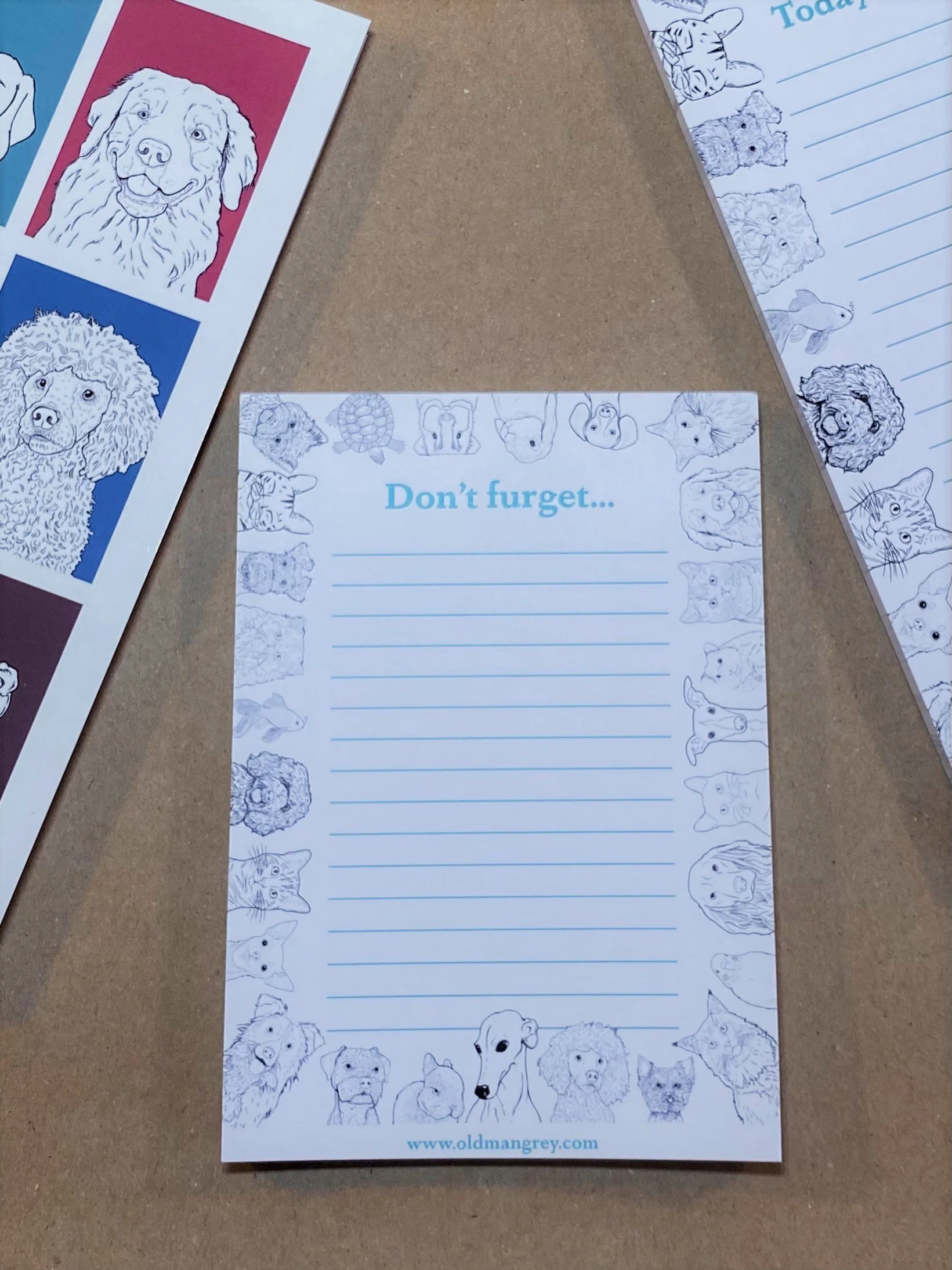 An A6 memo pad titled 'Don't Furget'. It has a black & white border of digitally illustrated pets! On a brown paper surface, with other pet-themed stationery visible at the edges.