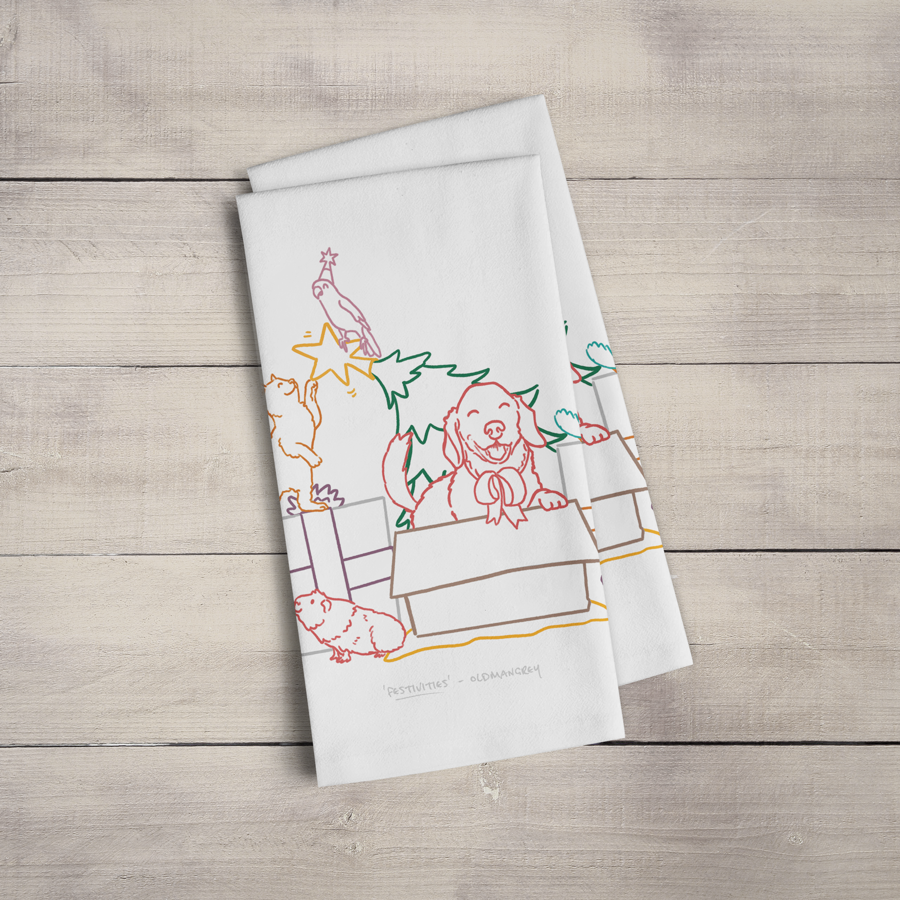 Two large tea towels folded to a rectangle & fanned out, on a wooden surface. Part of the design can be seen - colourful digitally illustrated pets on & around gifts & a Christmas tree!