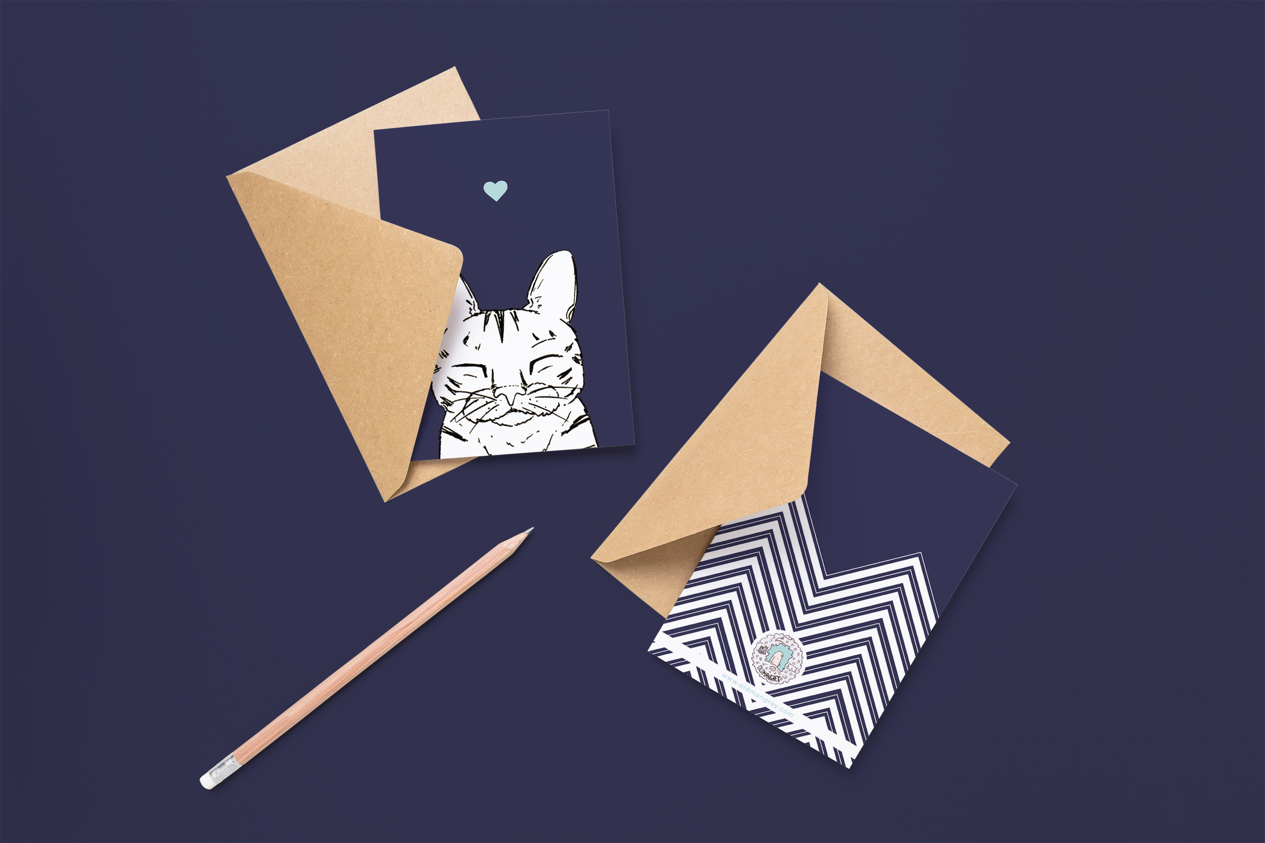Two cards on brown envelopes, one face up one down. The card and image have a navy coloured background, with a black & white digital illustration of the head & shoulders of a stripy sleepy cat.