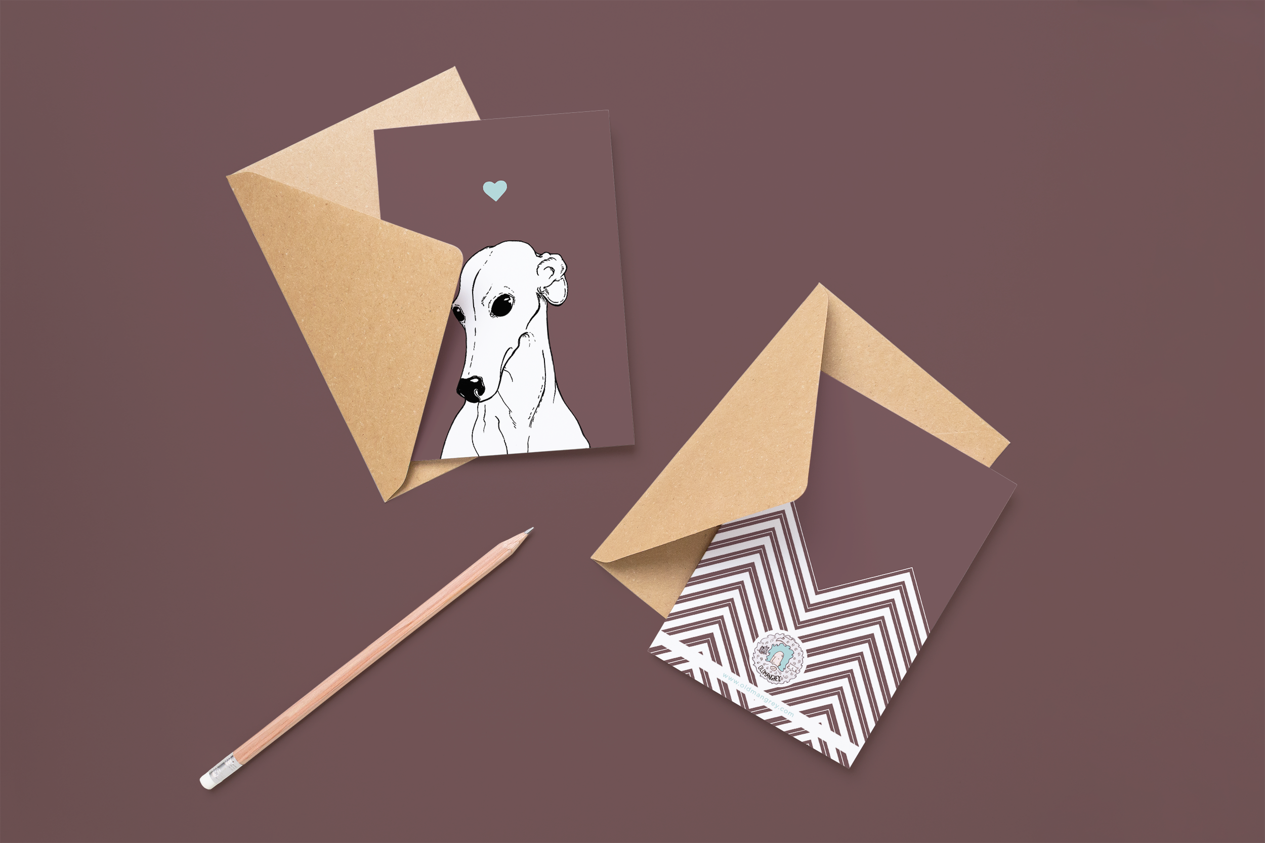 Two cards on brown envelopes, one face up one down. The card and image have a deep purple coloured background, with a black & white digital illustration of the head & shoulders of a Greyhound dog.