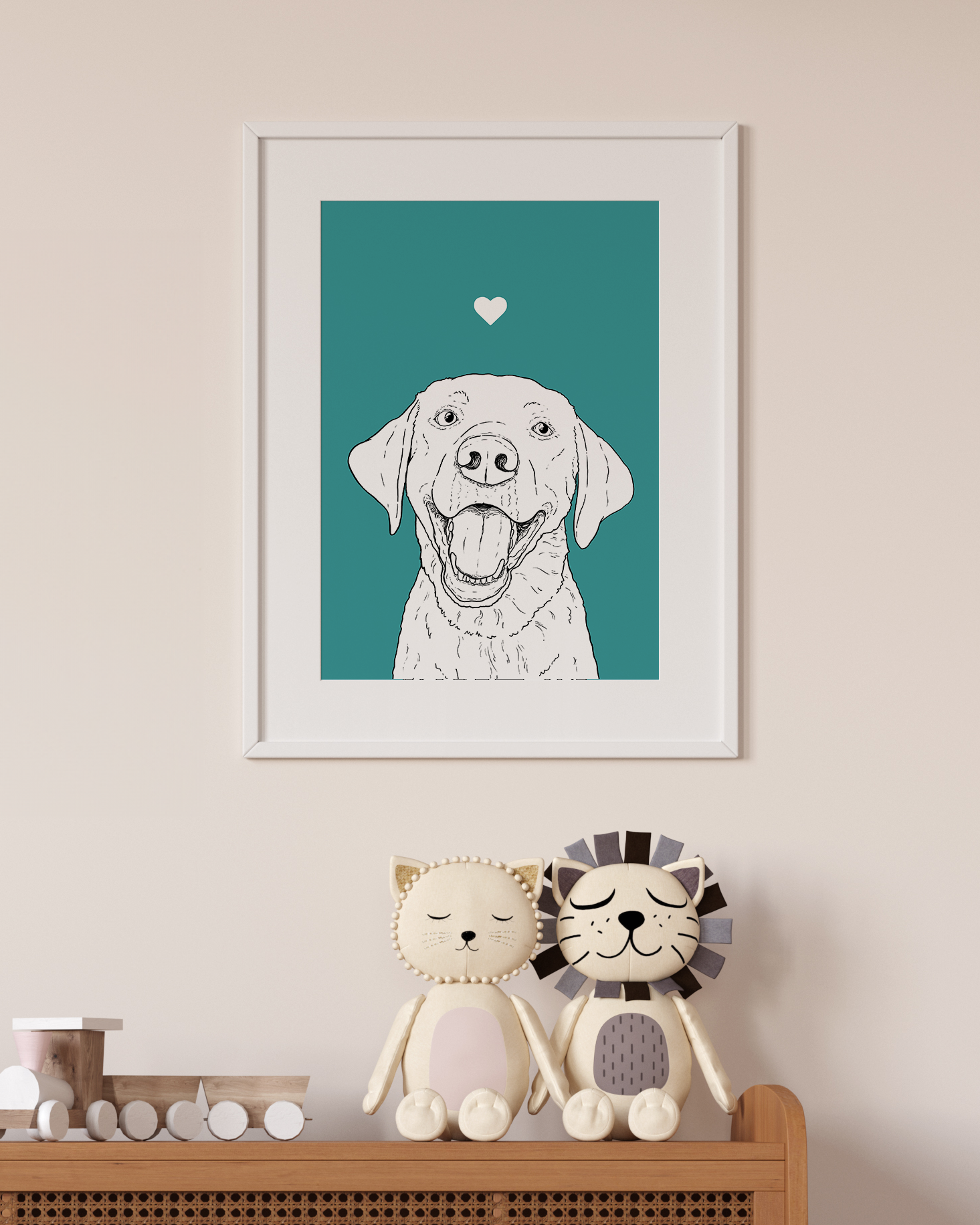 An A4 print in a white frame on a wall above 2 lion toys sitting on a unit. It has a black & white illustration of the head & shoulders of a Labrador dog on a turquoise background.