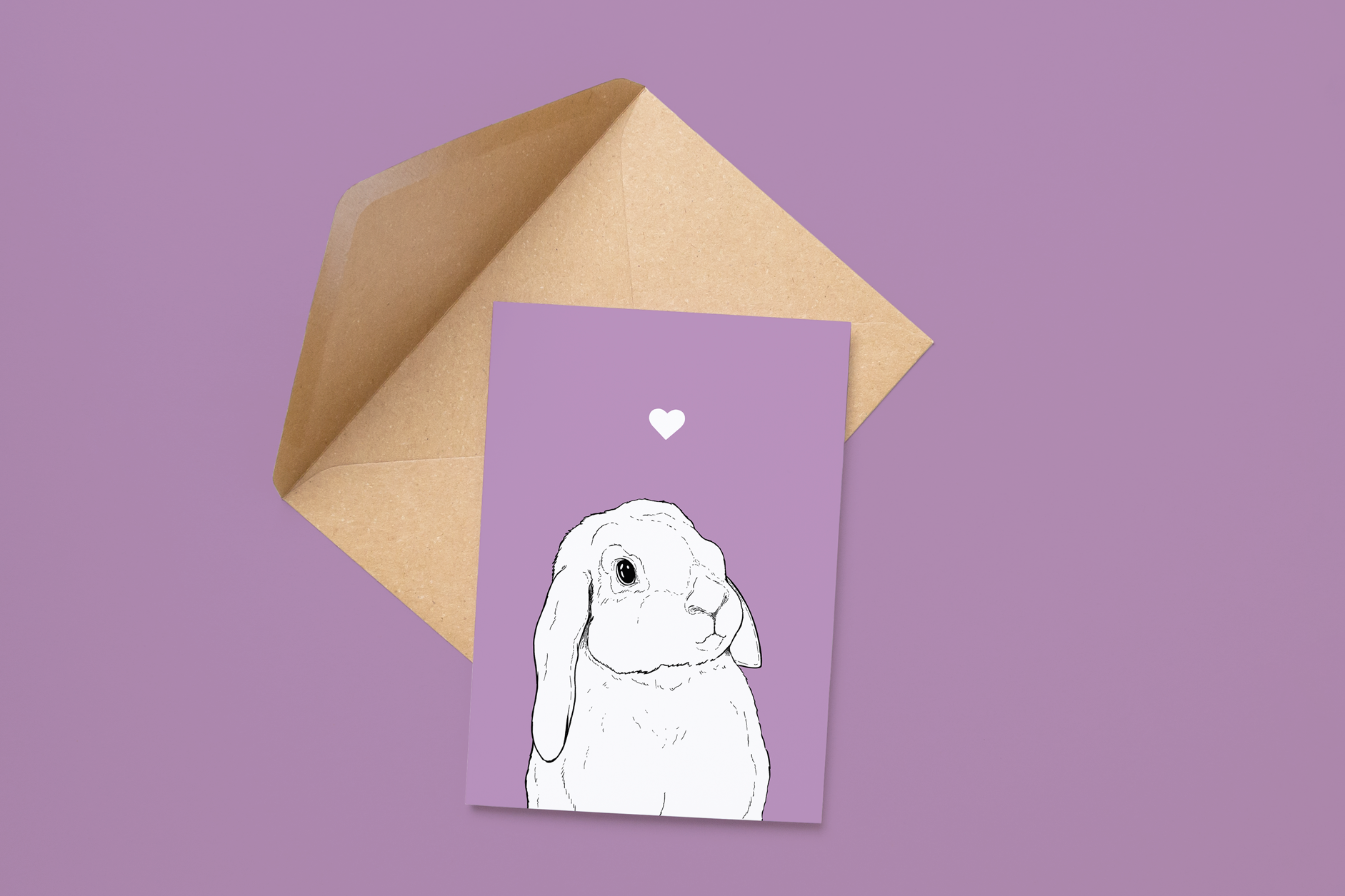 An A6 greetings card on a brown envelope. The card & image have a lilac purple background, with a black & white digital illustration of the head & shoulders of a Lop Eared bunny.