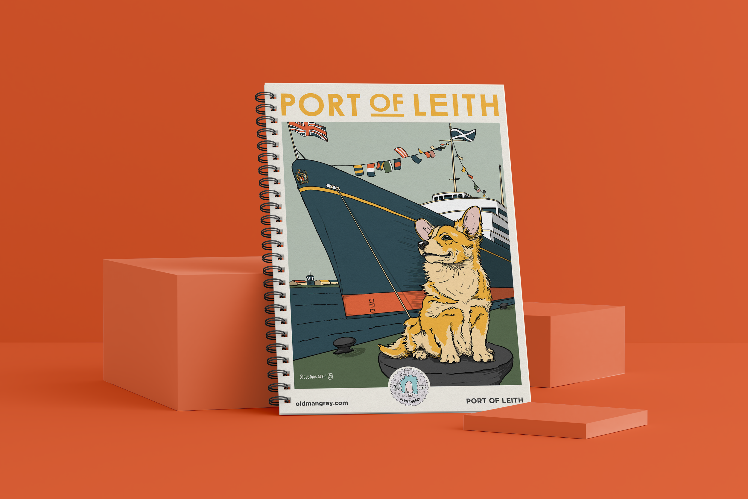 My A5 Corgi Leith wire bound notebook against a red backdrop. It has a digital illustration of a Corgi dog sat in front of the Royal Yacht Britannia under the title 'Port of Leith'.