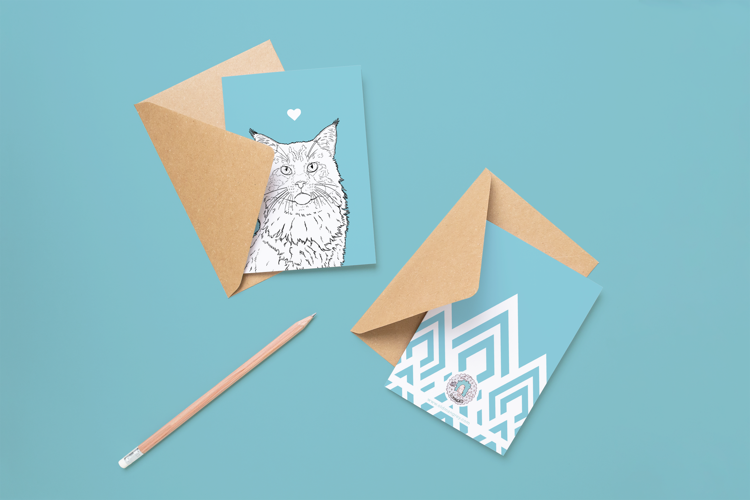 Two cards on brown envelopes, one face up one down. The card and image have a pale blue coloured background, with a black & white digital illustration of the head & shoulders of a Maine Coon cat.