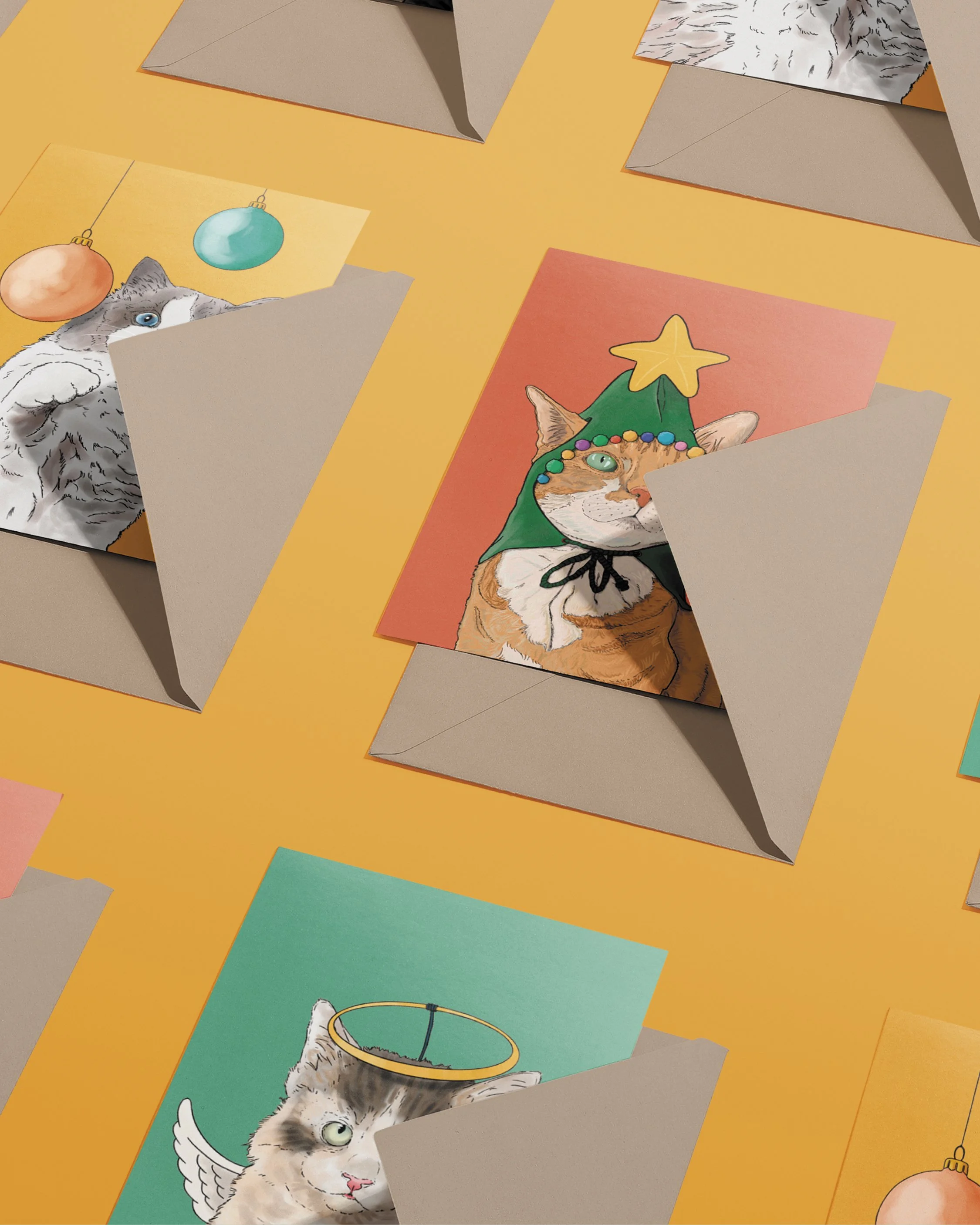 3 x A6 Cat Christmas Cards, bright digital illustrations including a ginger cat in a green Christmas tree hat! Copies tucked into brown envelopes, set on a flat yellow gold background.