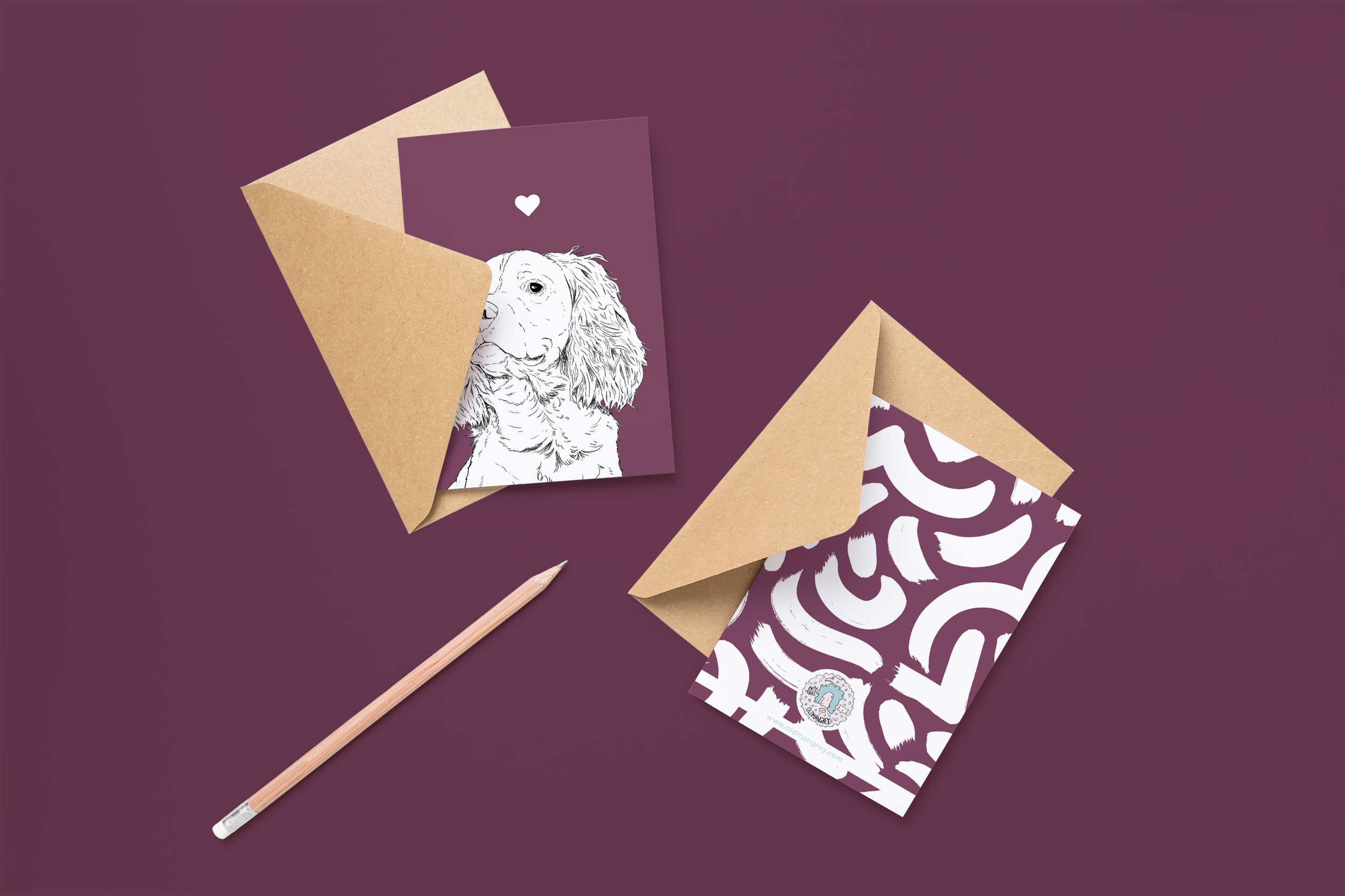 Two cards on brown envelopes, one face up one down. The card and image have a purple coloured background, with a black & white digital illustration of the head & shoulders of a Springer Spaniel dog.