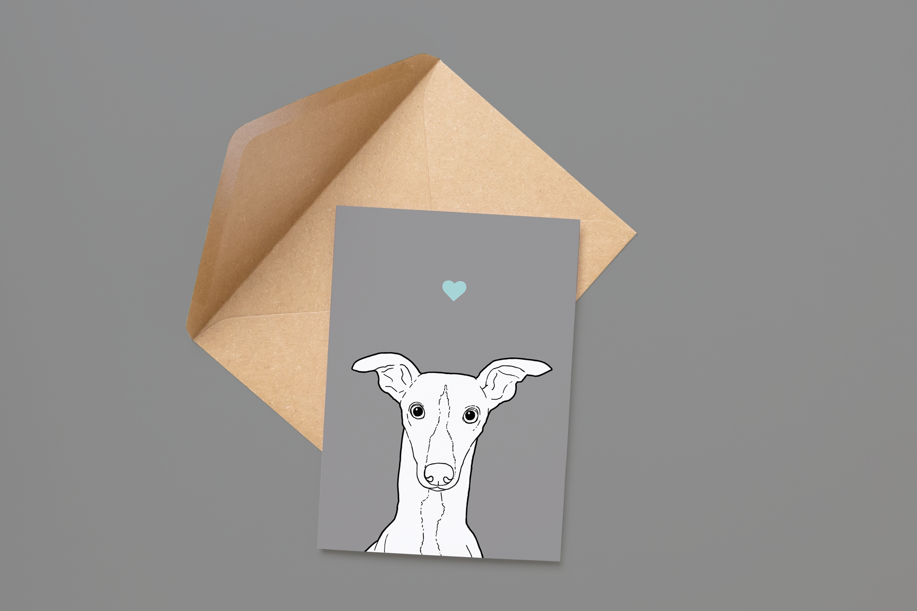 An A6 greetings card on a brown envelope. The card & image have a pale grey background, with a black & white digital illustration of the head & shoulders of a Whippet dog.
