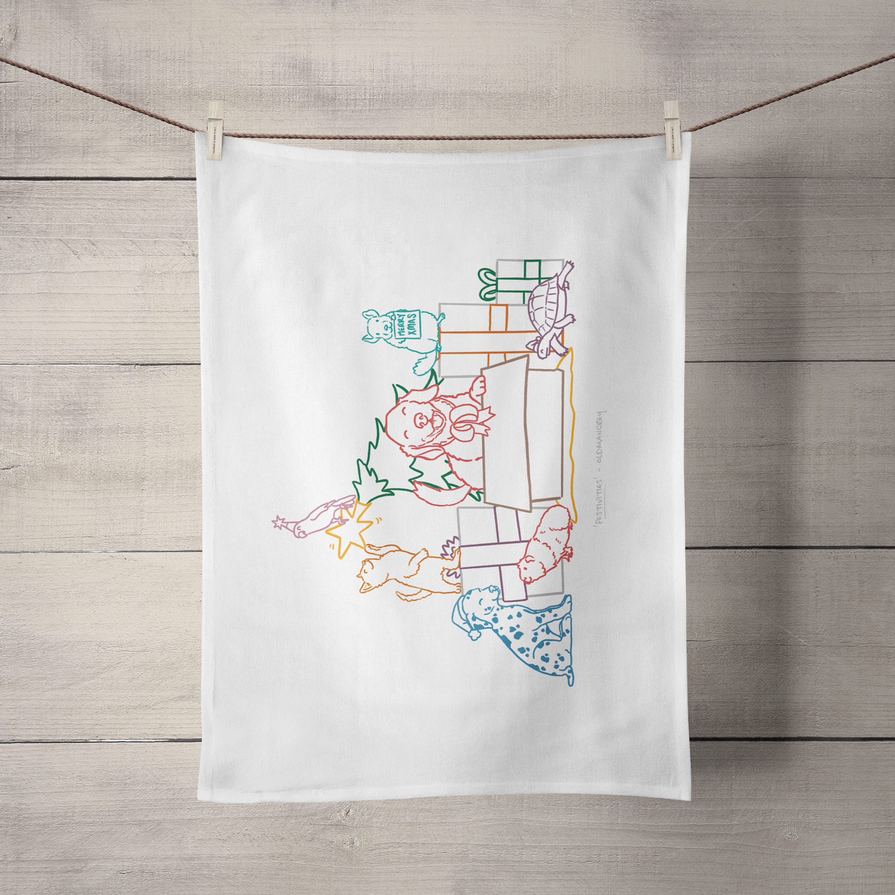 A large tea towel hanging by its short side from a piece of string. It has a colourful digital illustration of of 7 pets opening Christmas presents & playing with the Christmas tree!