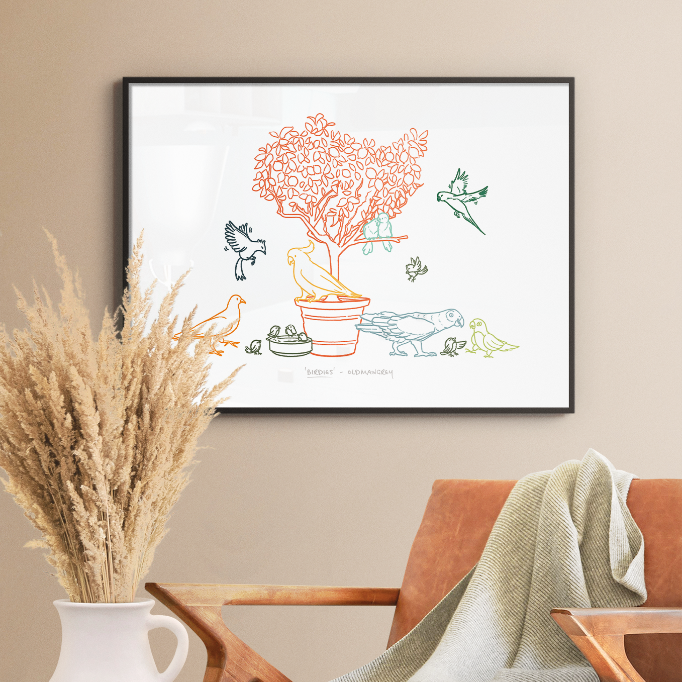 An A3 print in a thin dark frame on a white wall with soft light. A chair & dried flowers are in the foreground. The print has a colourful digital illustration of birds on & around a small tree.