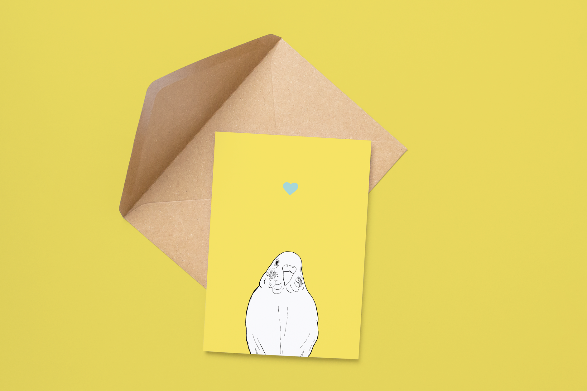 An A6 greetings card on a brown envelope. The card & image have a yellow background, with a black & white digital illustration of the head & shoulders of a budgie.