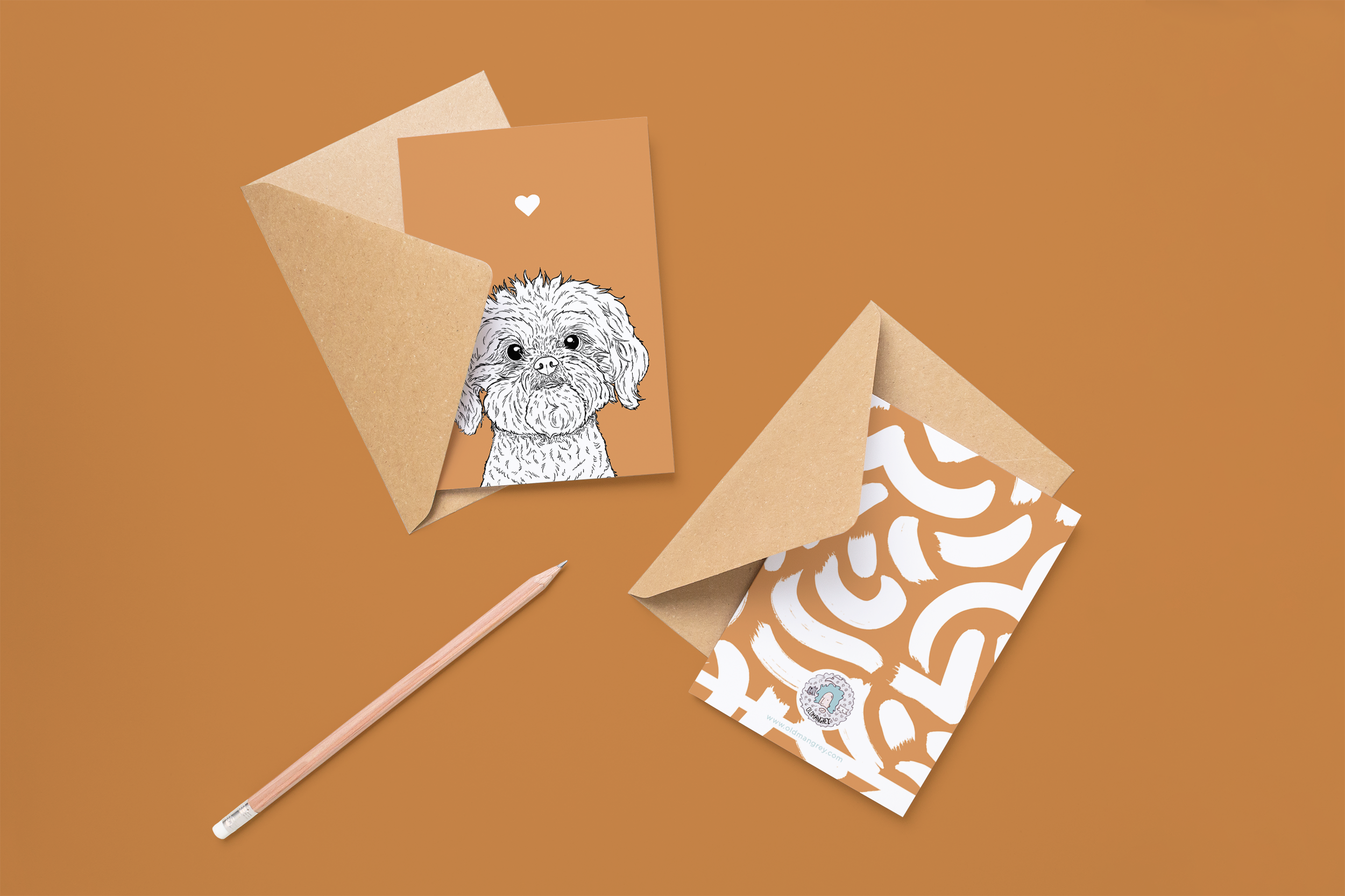 Two cards on brown envelopes, one face up one down. The card and image have an orange coloured background, with a black & white digital illustration of the head & shoulders of a Shih Tzu dog.