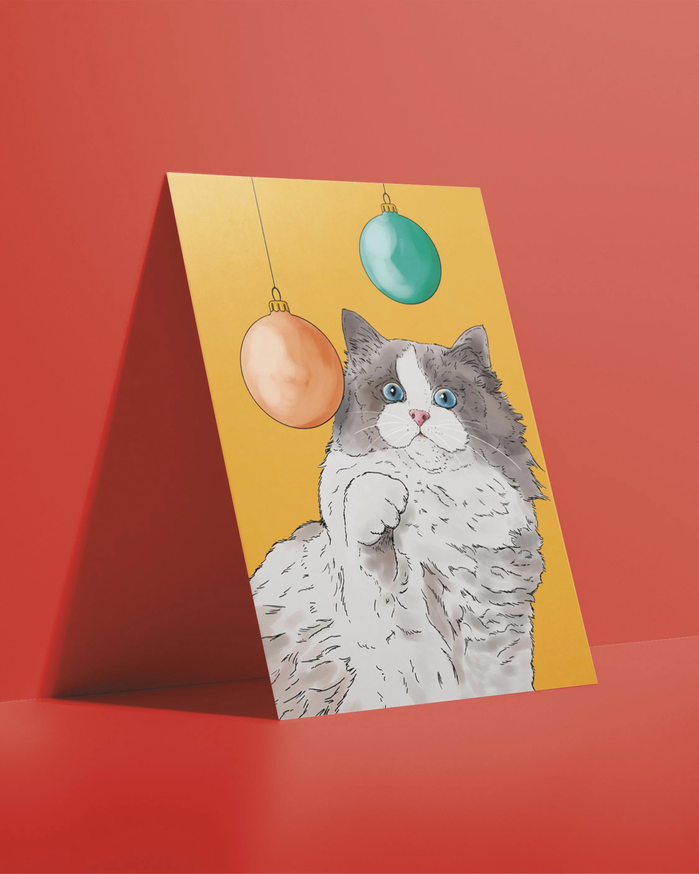 An A6 Cat Christmas Card, bright digital illustration of a grey Ragdoll cat batting Christmas baubles! Set on a flat gold yellow background.