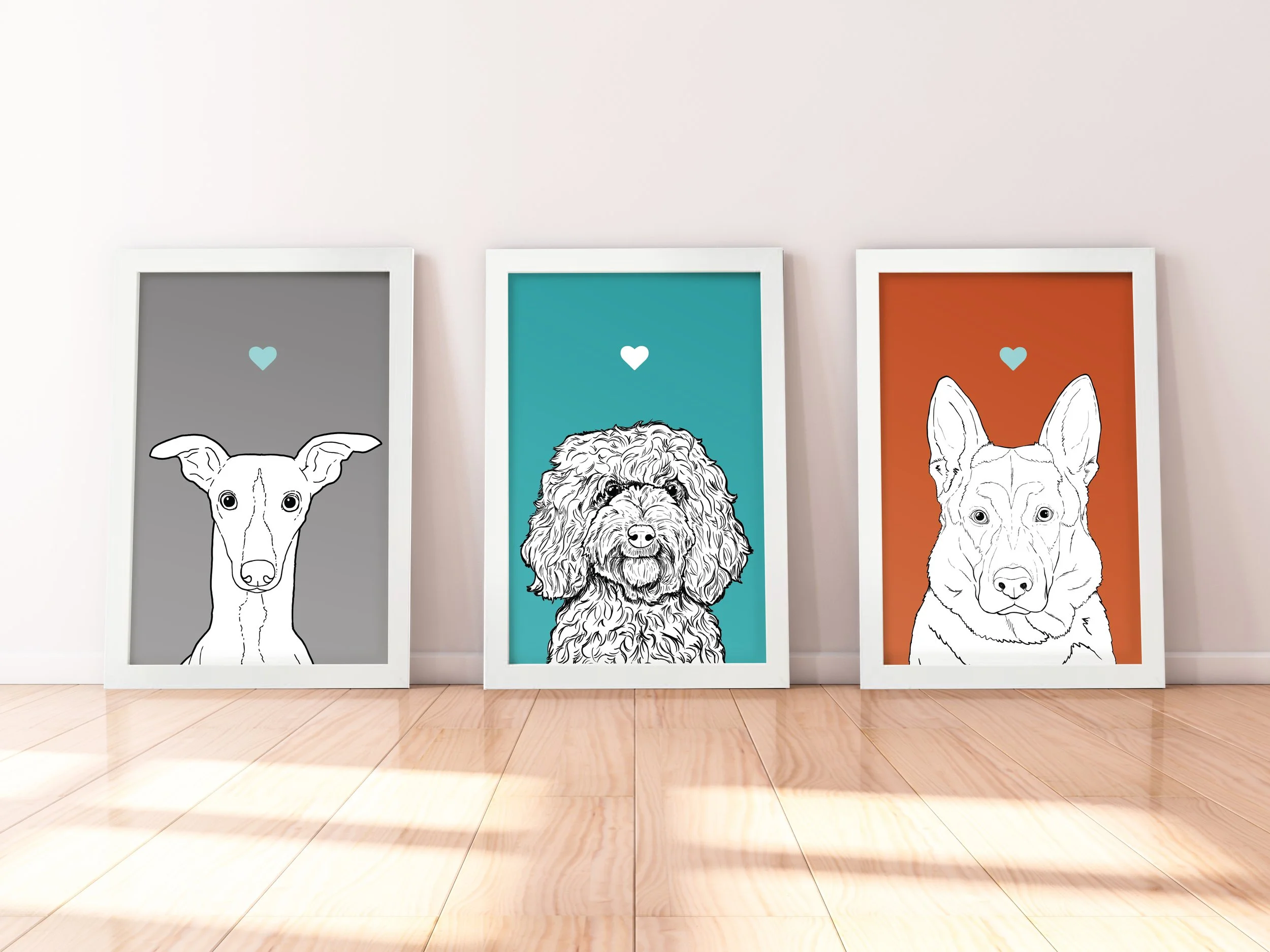 A trio of A4 prints in white wooden frames leaning against a white wall. Each has a black & white digital illustration of the head & shoulders of a different dog breed: Whippet, Cockapoo & Alsatian.