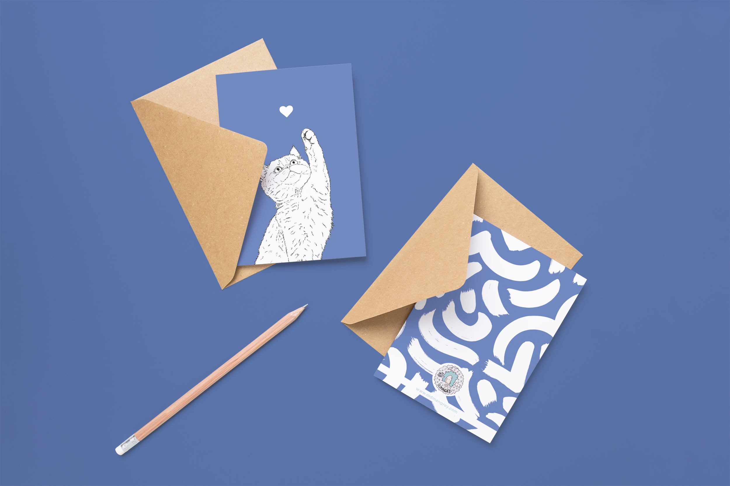 Two cards on brown envelopes, one face up one down. The card and image have a powder blue coloured background, with a black & white digital illustration of the head & shoulders of a kitten.
