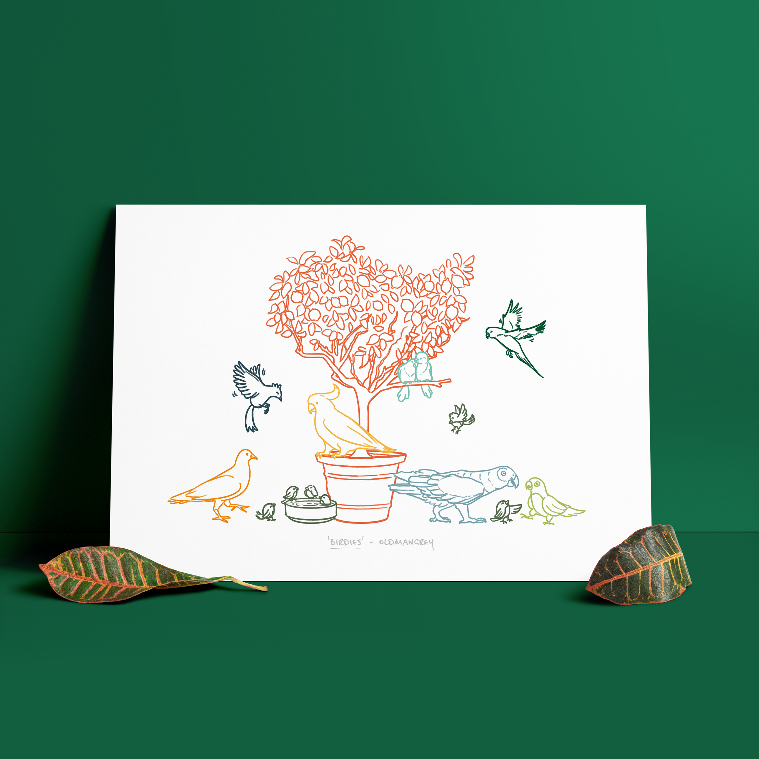 An A3 print set against a dark green backdrop, with two green leaves at the base. The print has a colourful digital illustration of birds on & around a small tree.