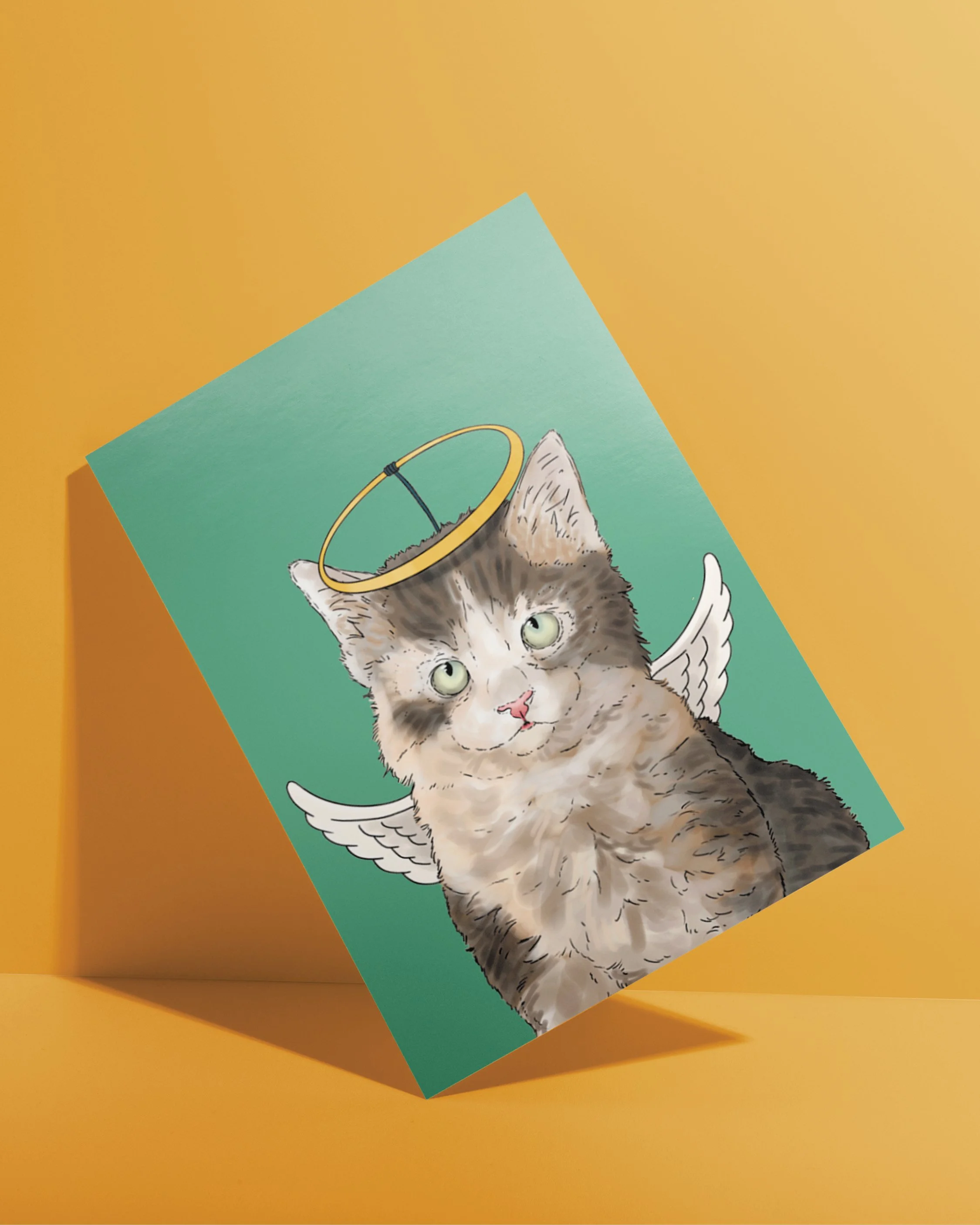 An A6 Cat Christmas Card, bright digital illustration of a grey kitten wearing an angel headdress! Set on a flat turquoise background.