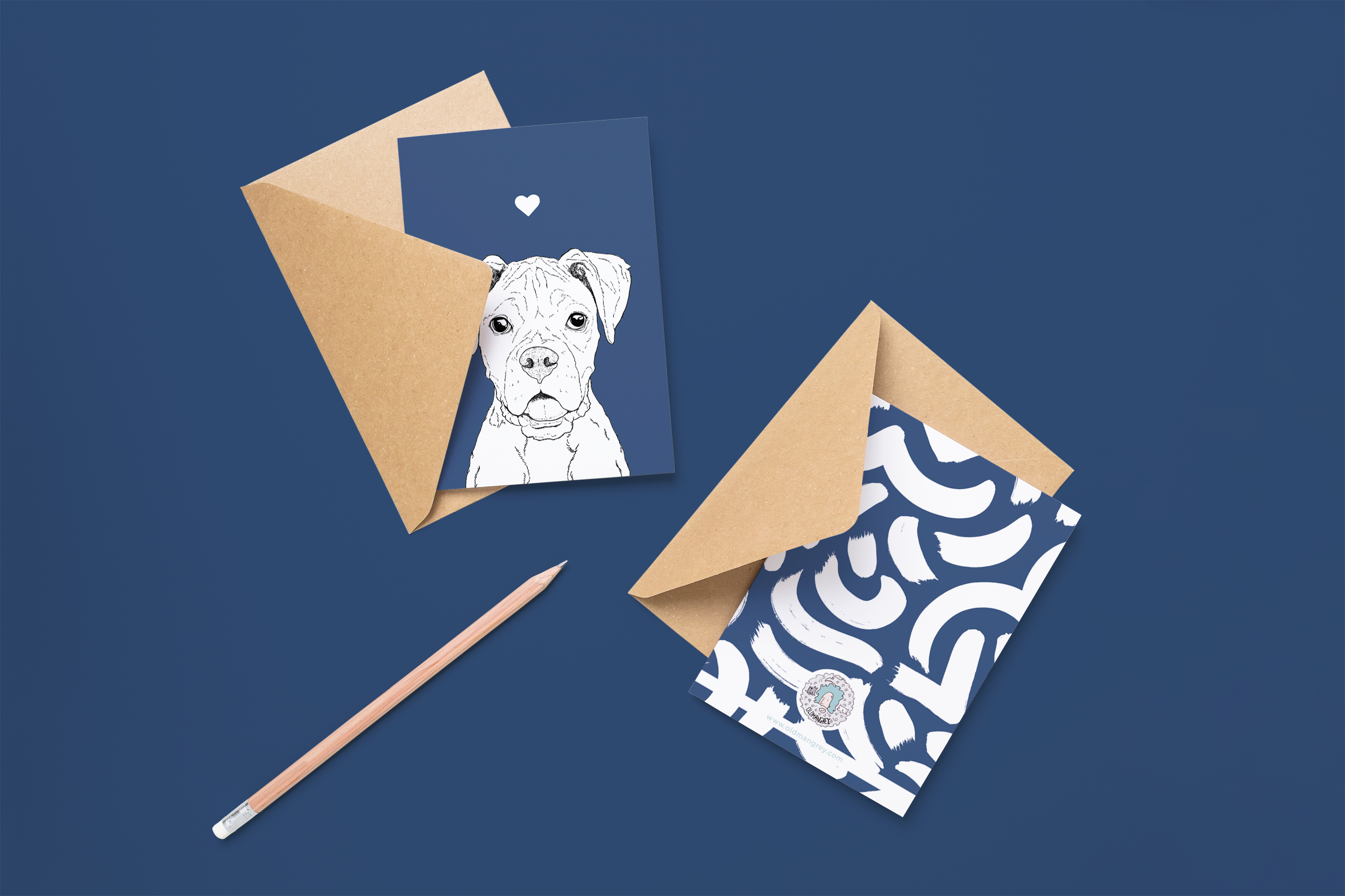 Two cards on brown envelopes, one face up one down. The card and image have a deep blue coloured background, with a black & white digital illustration of the head & shoulders of a Boxer dog.