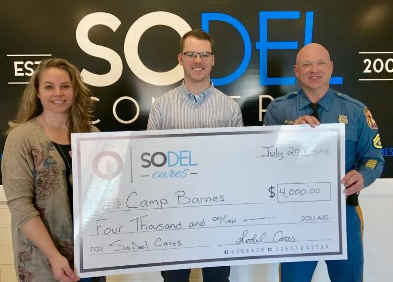 Check presentation attendees shown are (l-r) Lindsey Barry, SoDel Cares president and SoDel Concepts controller; Brenton Lyman, general manager of Matt's Fish Camp in Bethany Beach; and Master Cpl. James Hatfield of Camp Barnes. SUBMITTED PHOTO